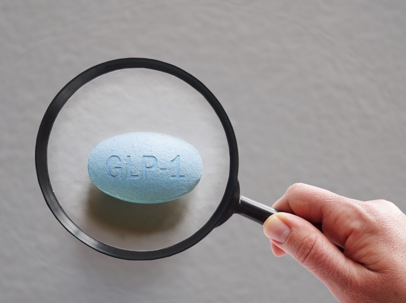 person using a magnifying glass to view a GLP-1 weight loss medication prescription option