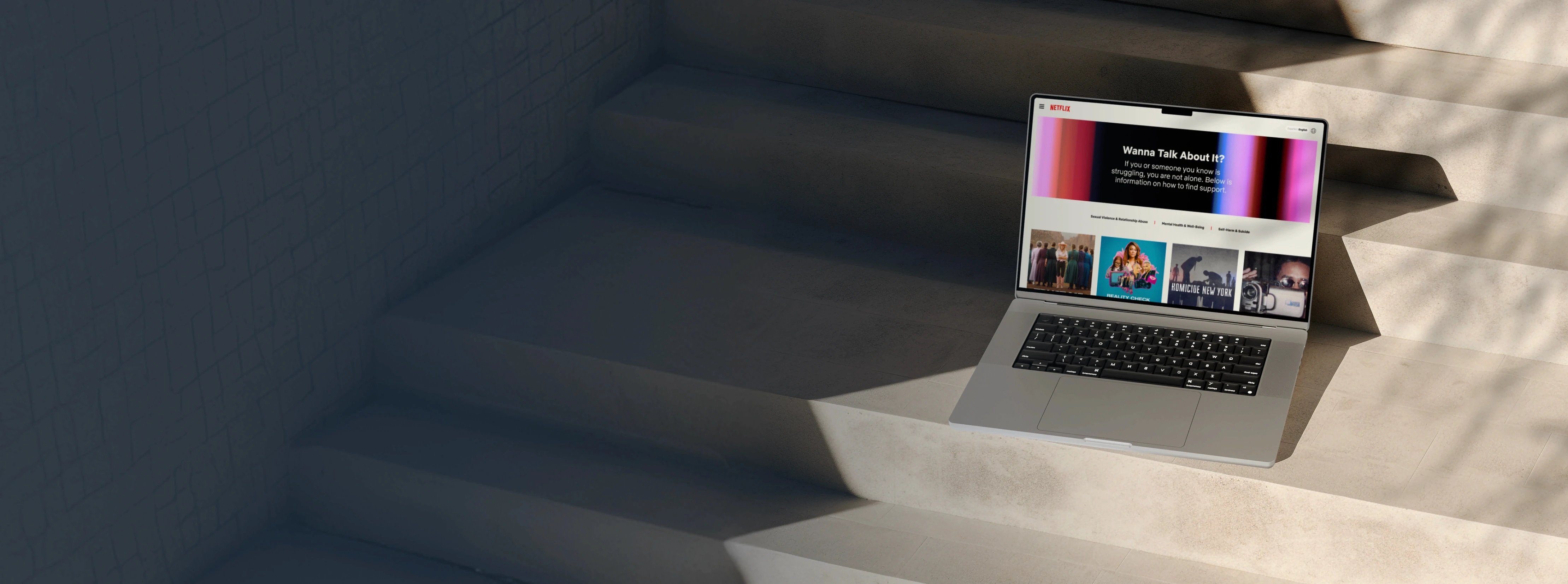 Homepage design for Netflix's global WannaTalkAboutIt.com, shown on a laptop outdoors.