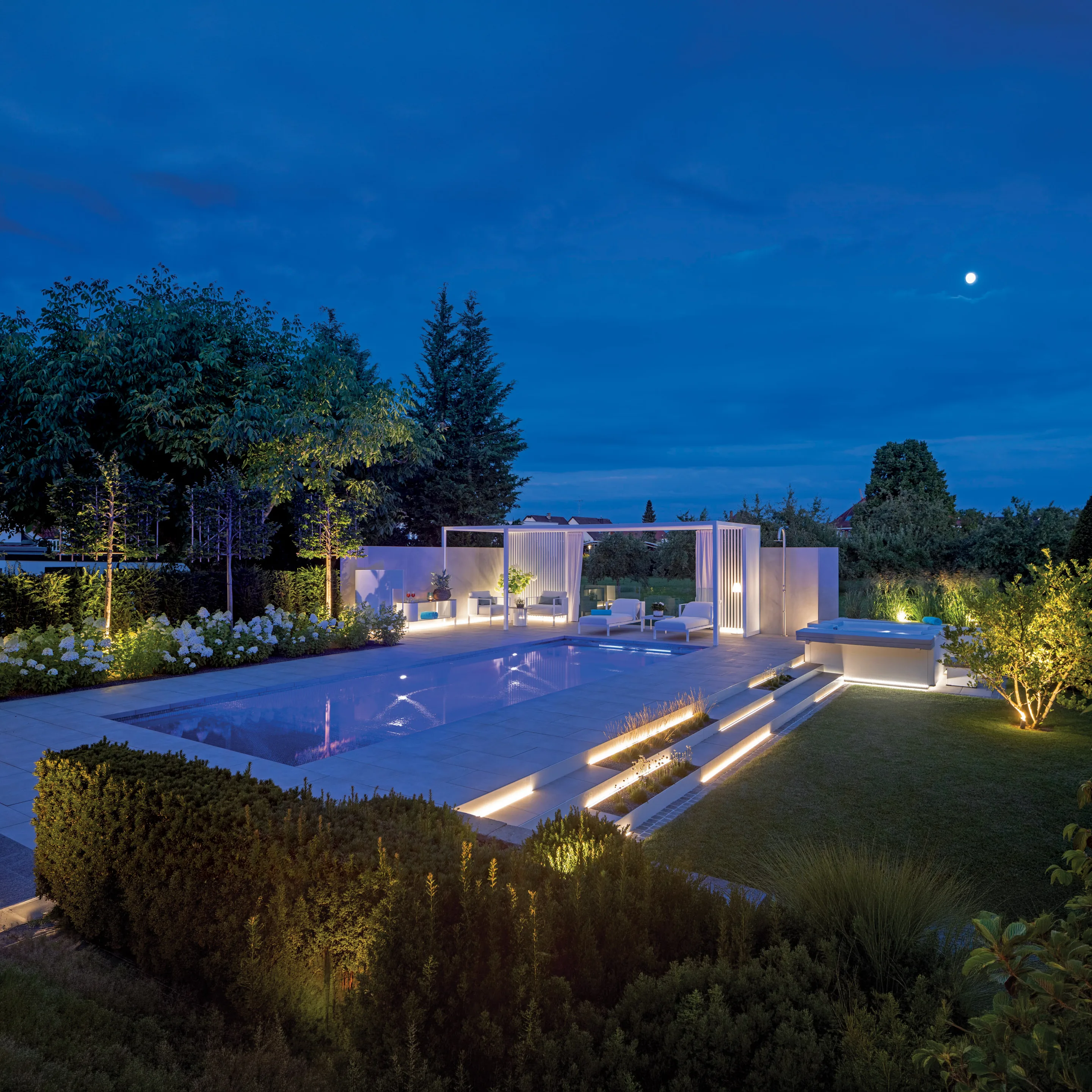 MLine Schwimmbad bei Nacht mit beleuchteten Stufen, weißer Pergola und Gartenanlage