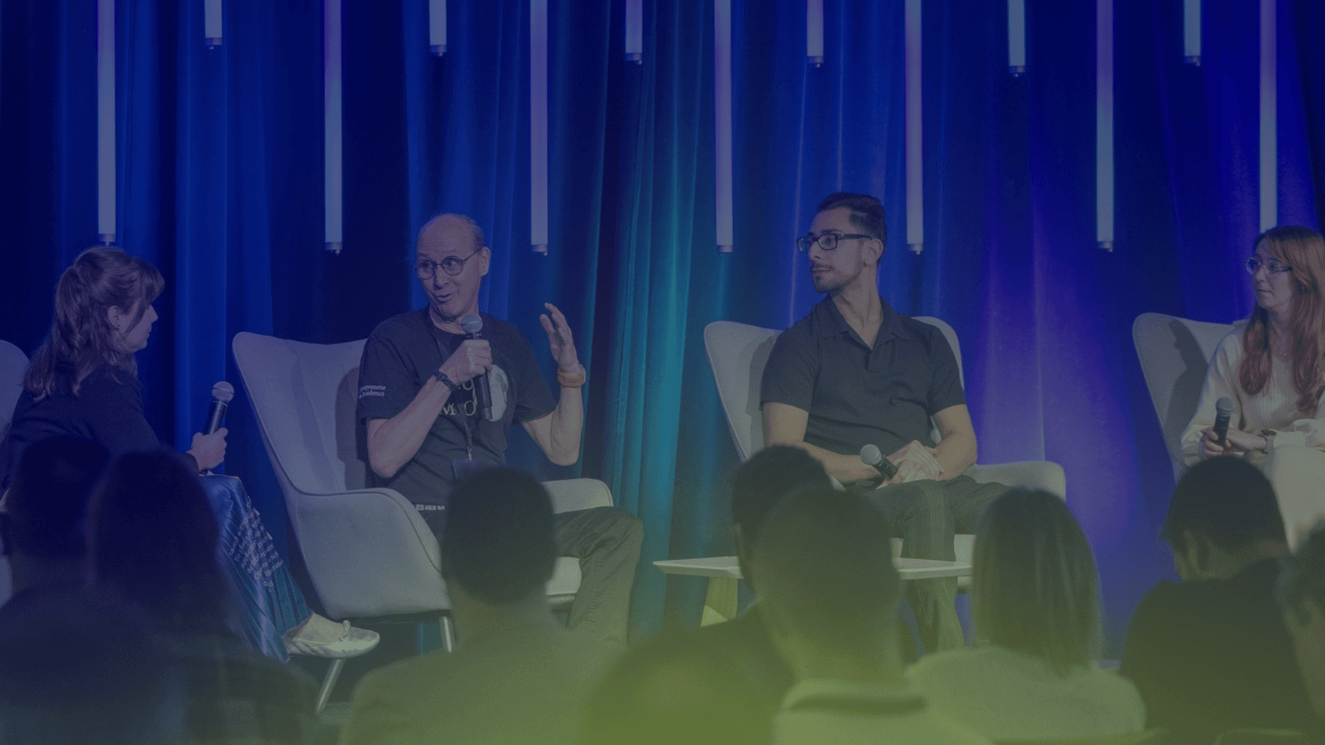 4 présentateurs s'exprimant devant un public sur fond bleu