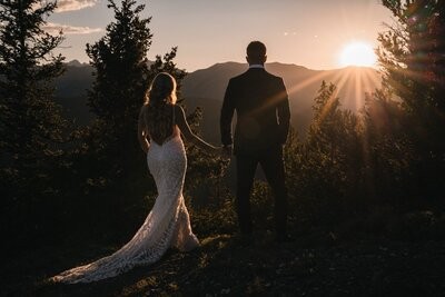 The newlyweds face the setting sun, with the bride's train trailing behind them.