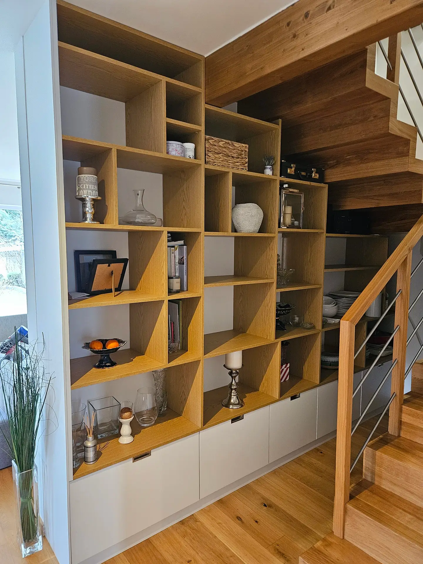 Monumentalna drewniana zabudowa biblioteczna na wymiar z otwartymi półkami w salonie.