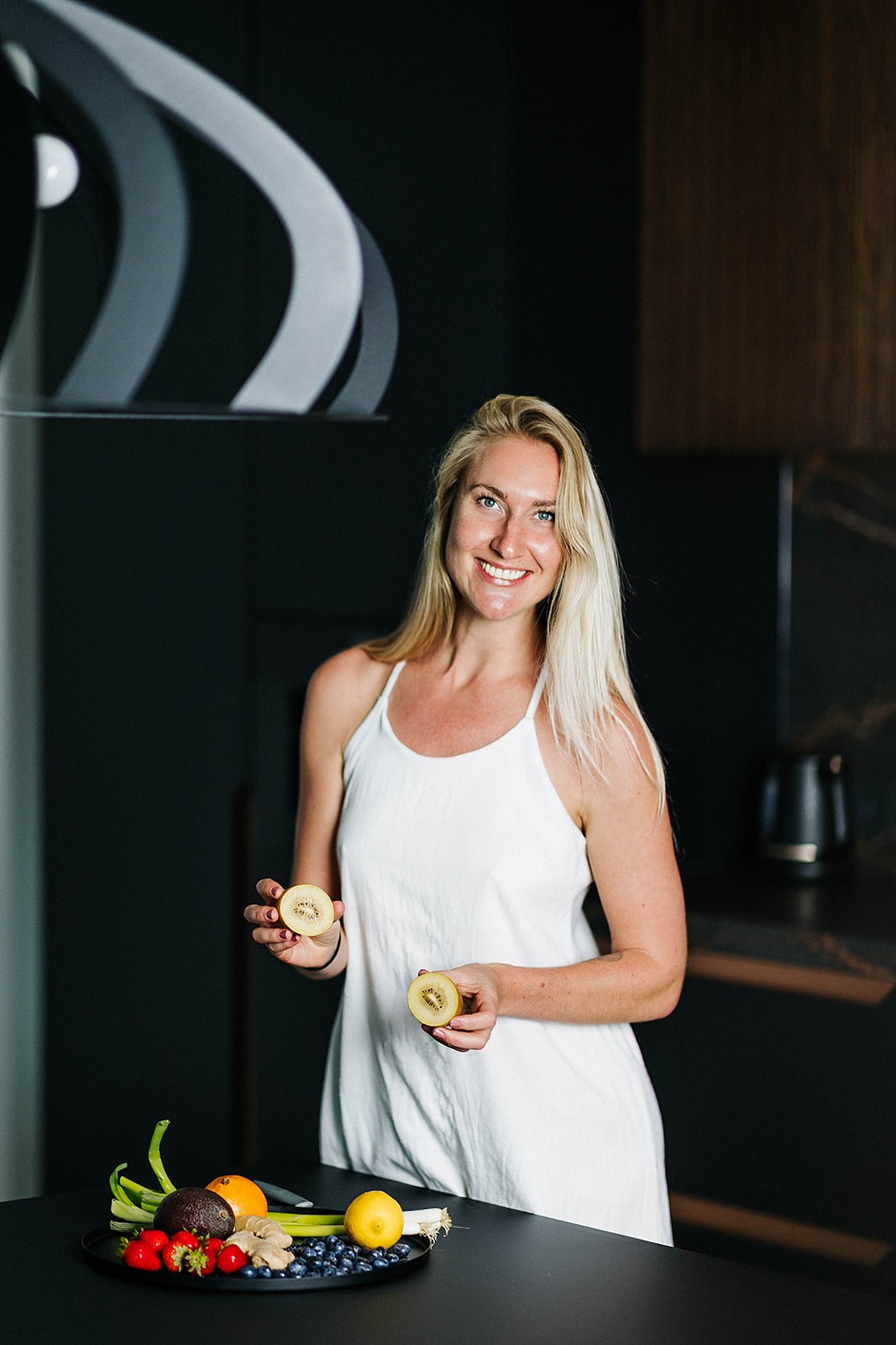 Daphne Medema van Hormone Healing Hub lachend met een kiwi in de hand, als voorbeeld van voeding die helpt bij PMS-klachten.