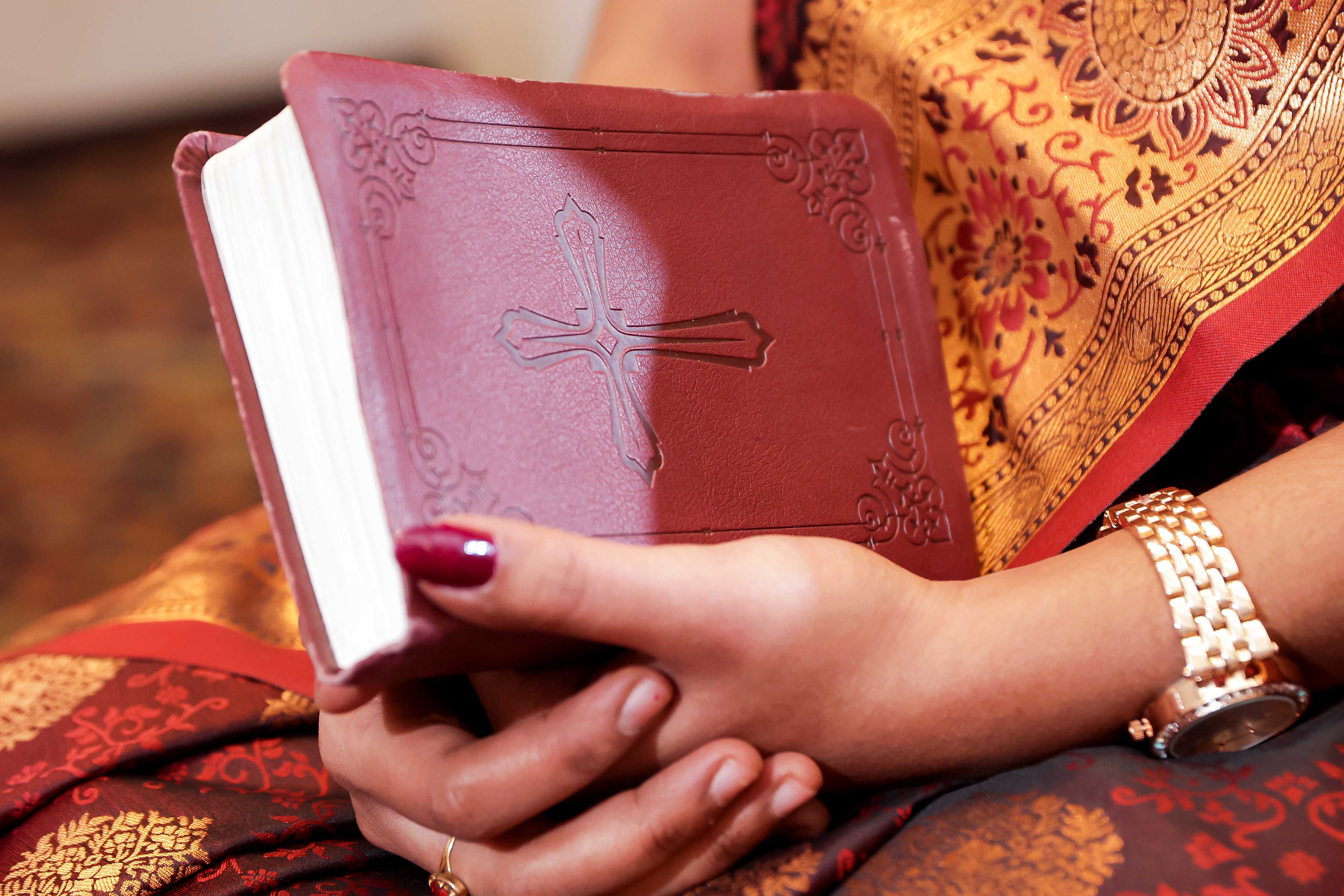 A couple stands on a sandy hill at sunset, facing away, with arms raised in a relaxed "hang loose" gesture. The scene conveys tranquility and joy.