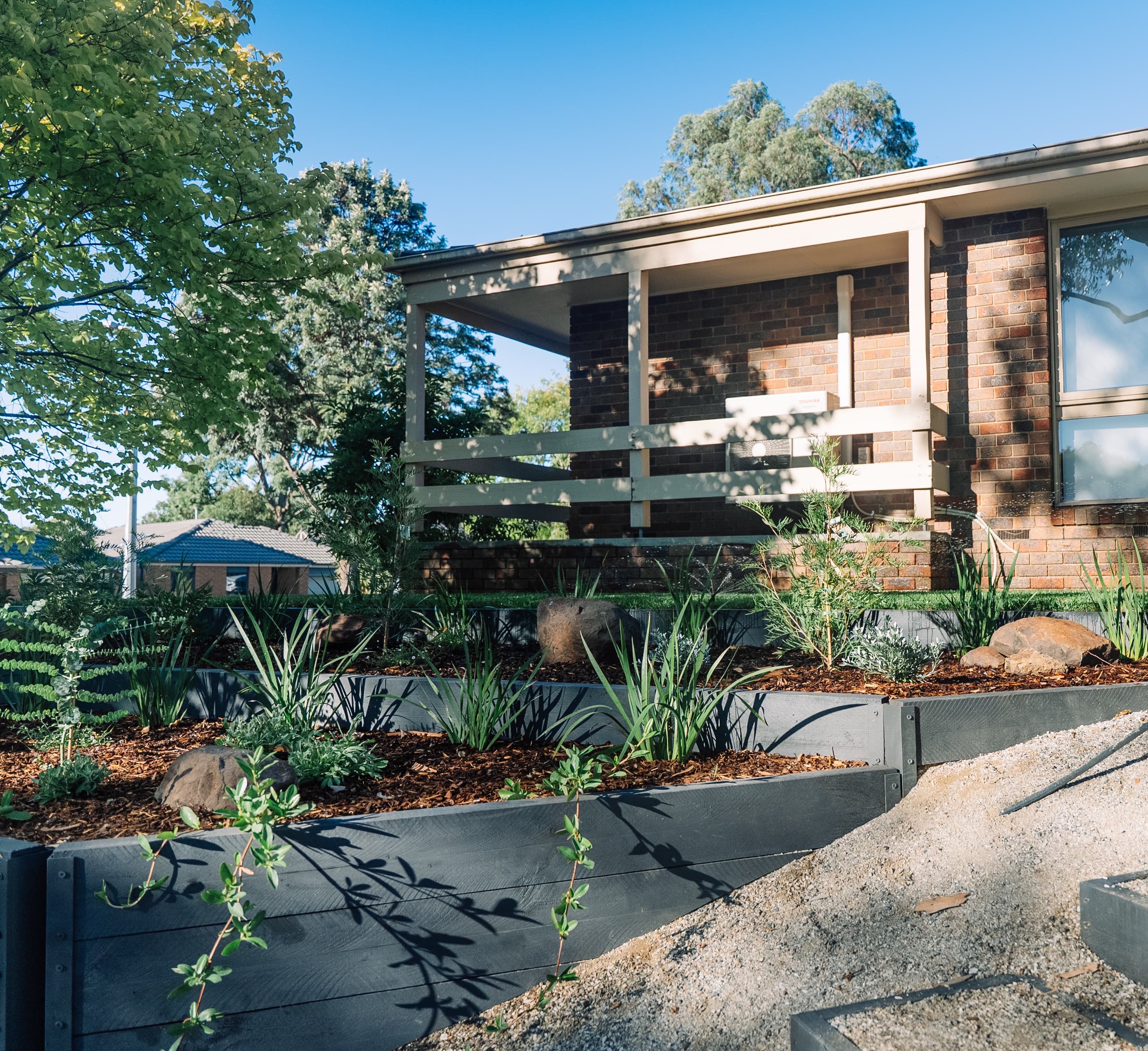 Brick house with a tiered front garden retaining wall and gravel path.