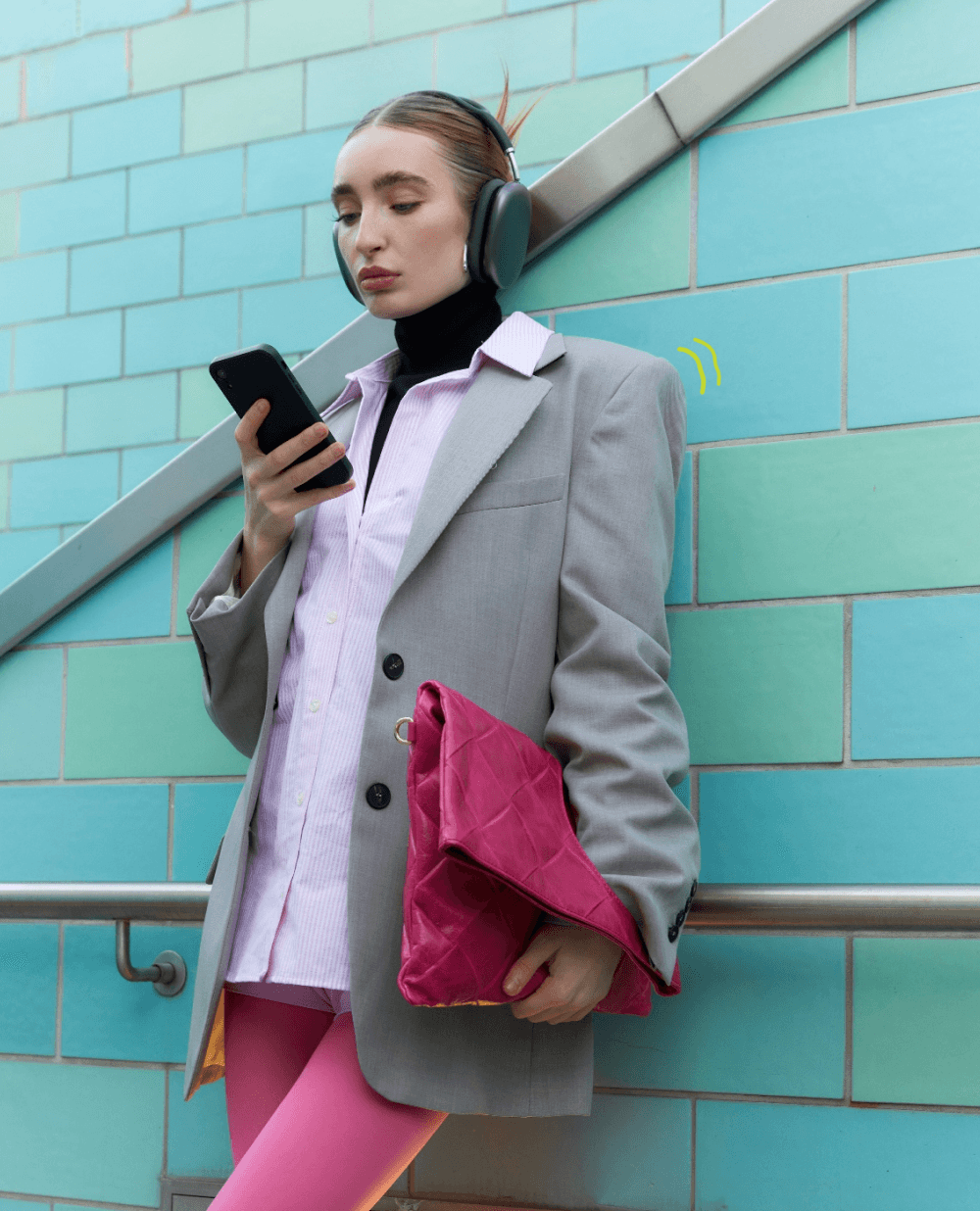 Woman using her phone against a turquoise tiled wall