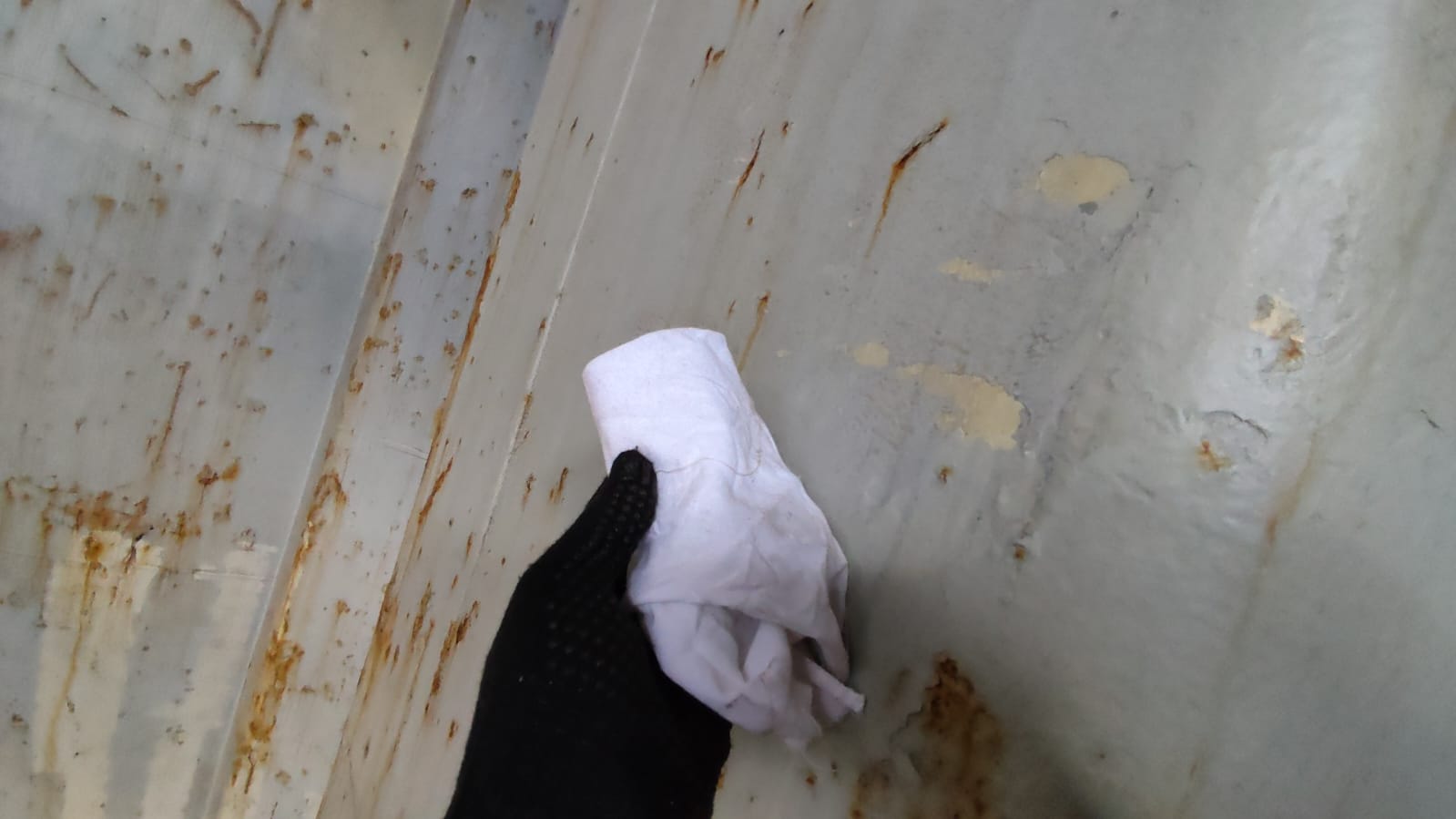 Seachios shore gang performing a white rag wipe test on cargo hold structure after cleaning, verifying residual dust after coal cargo.