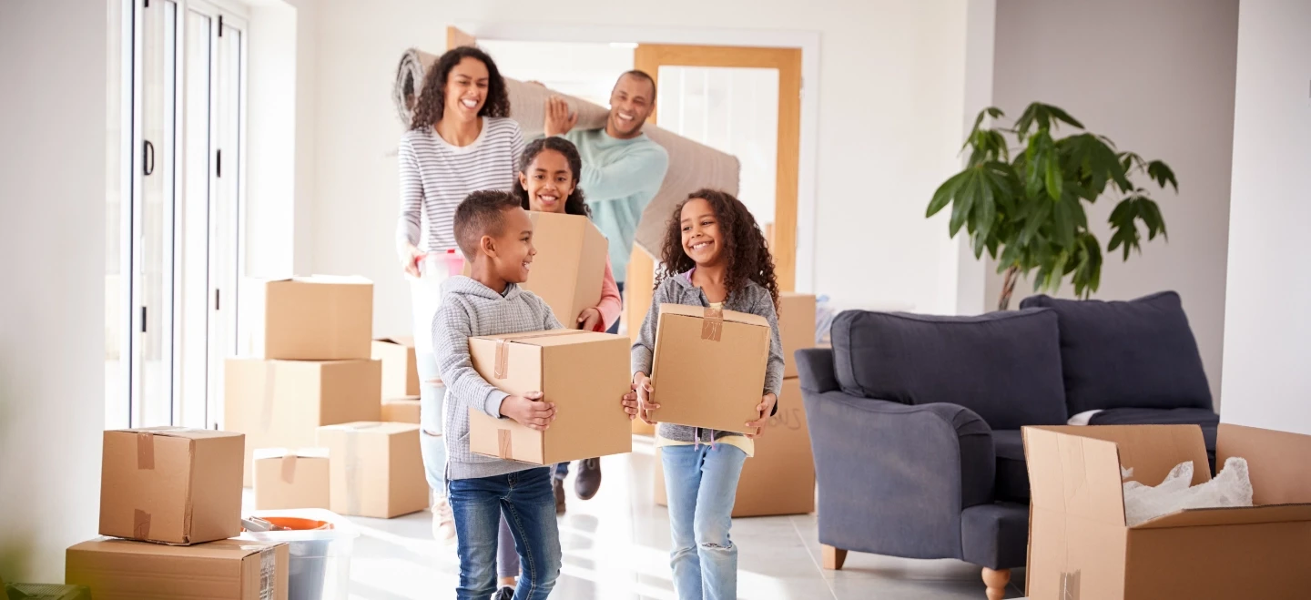 Mixed race family holding boxes moving into a new home.