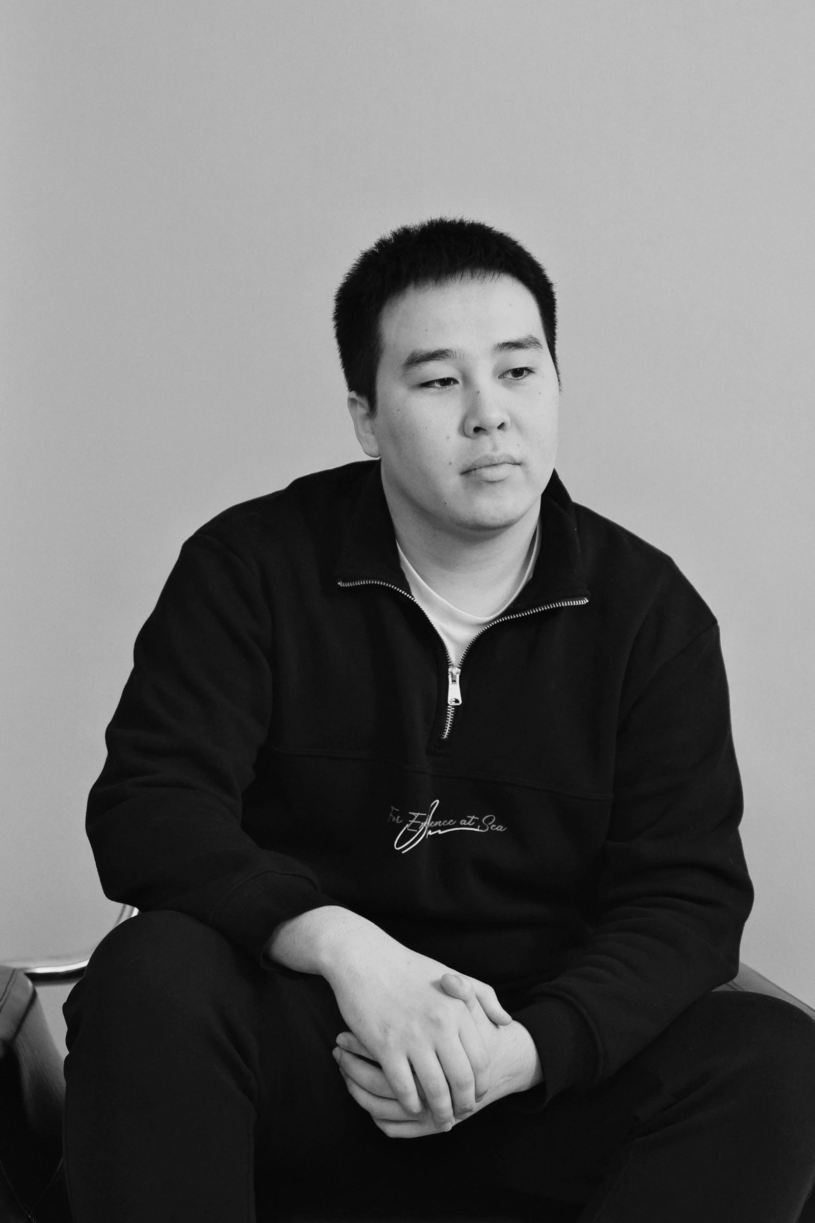A woman seated at a desk in a minimalist workspace, reviewing architectural models. Large windows offer a view of a serene wooded area.
