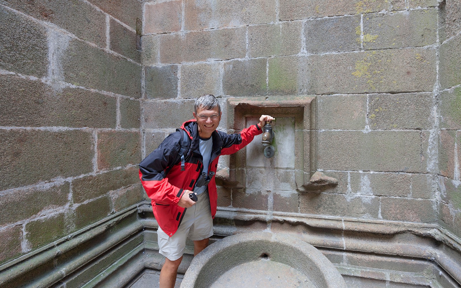 Visitor at Mont Saint-Michel fountain during Paris day trip.