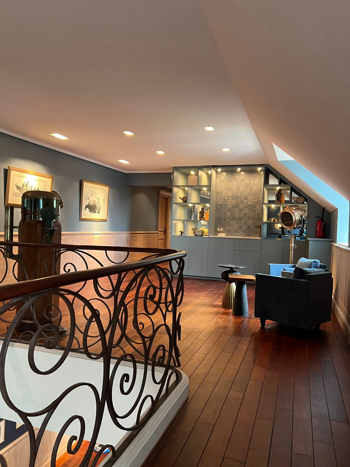 Palier avec éclairage lumineux rampe en fer forgé, parquet en bois et bibliothèque design