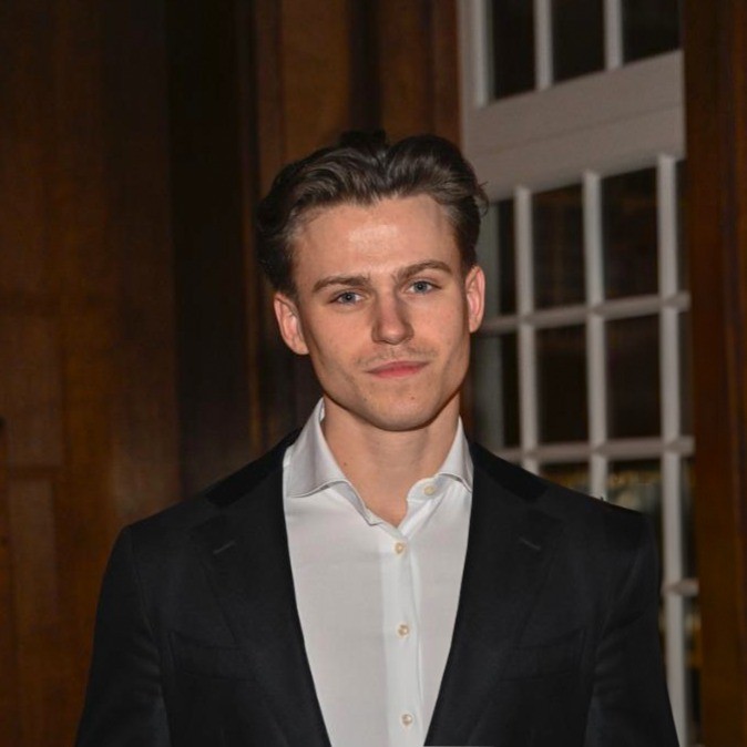 Portrait of a laughing person with curly hair wearing a white shirt