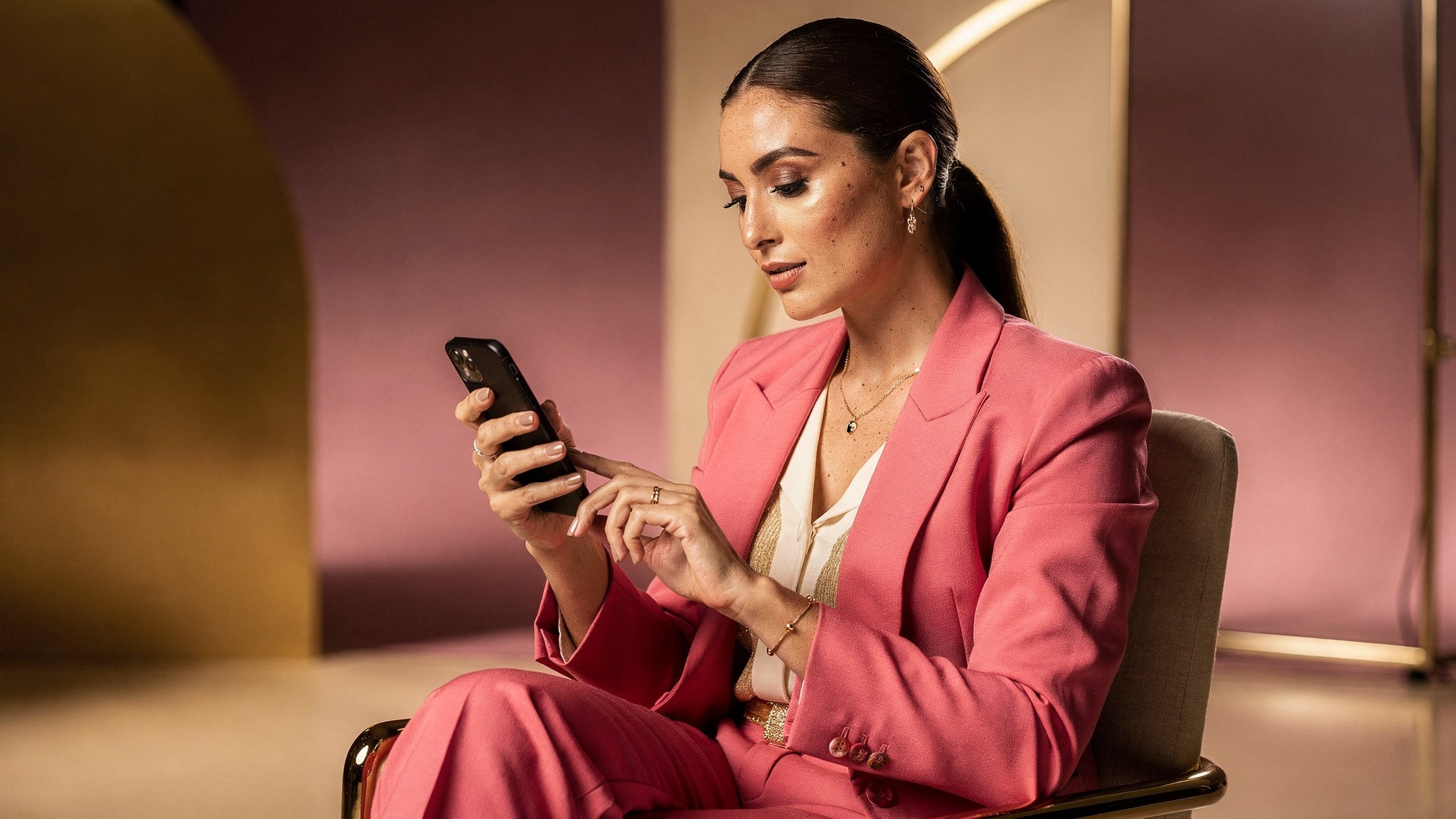 Creator sitting and tapping through application steps on her phone with focused calm expression