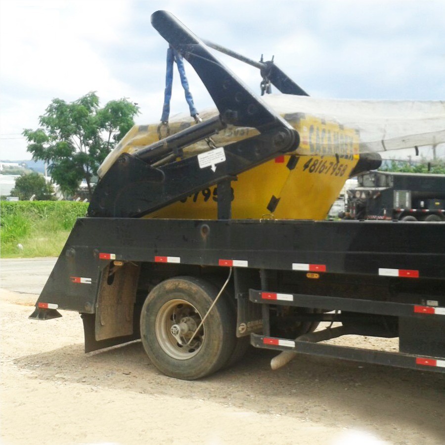 Caminhão posicionando caçamba na rua.