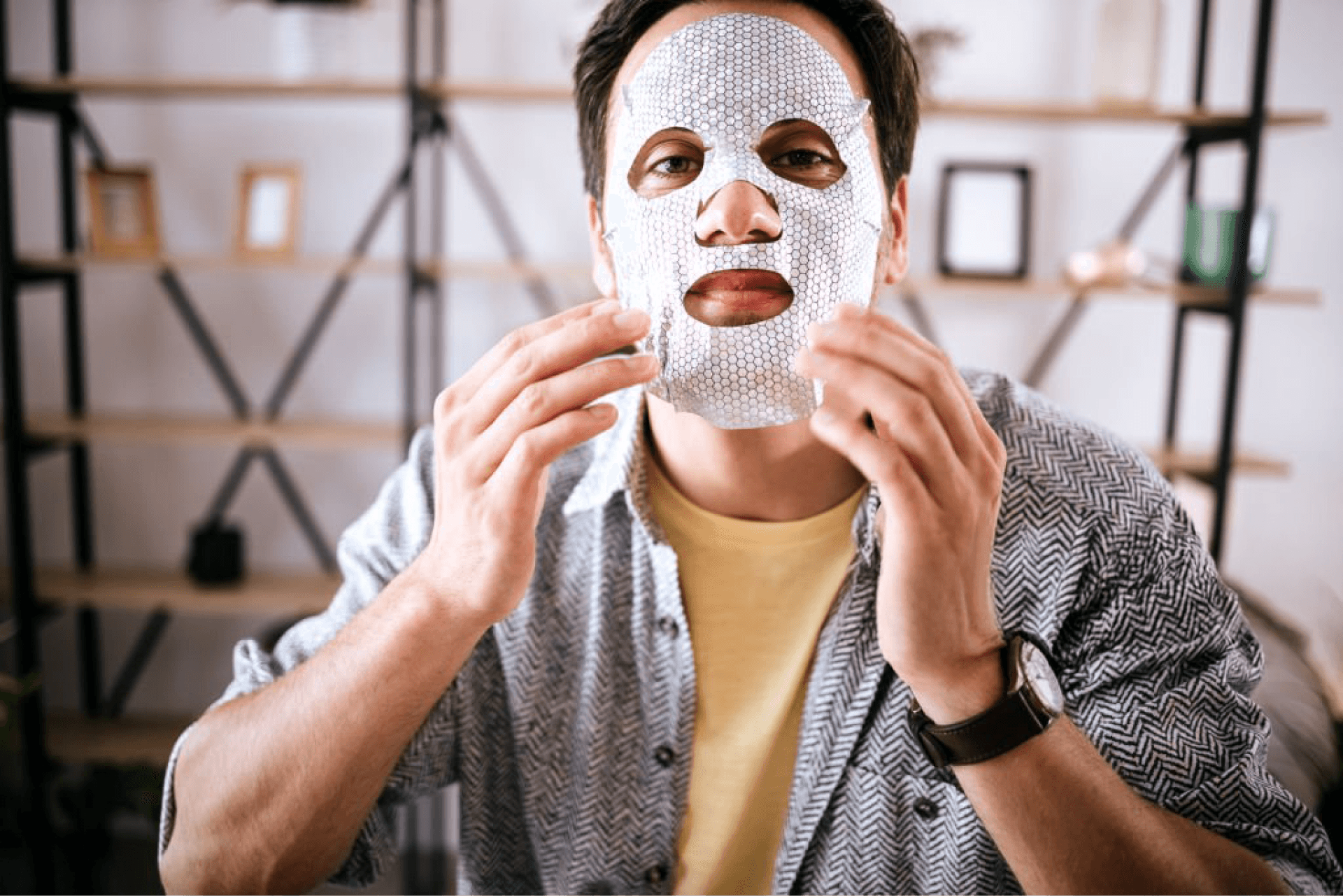 Young man applying a hydrating sheet mask for skincare at home, highlighting self-care for men