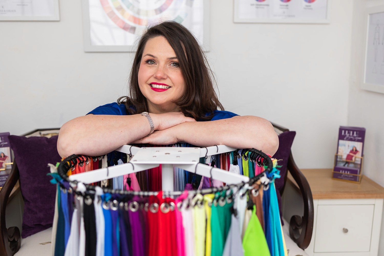 Lucy with arms crossed, smiling while leaning on her colour wheel