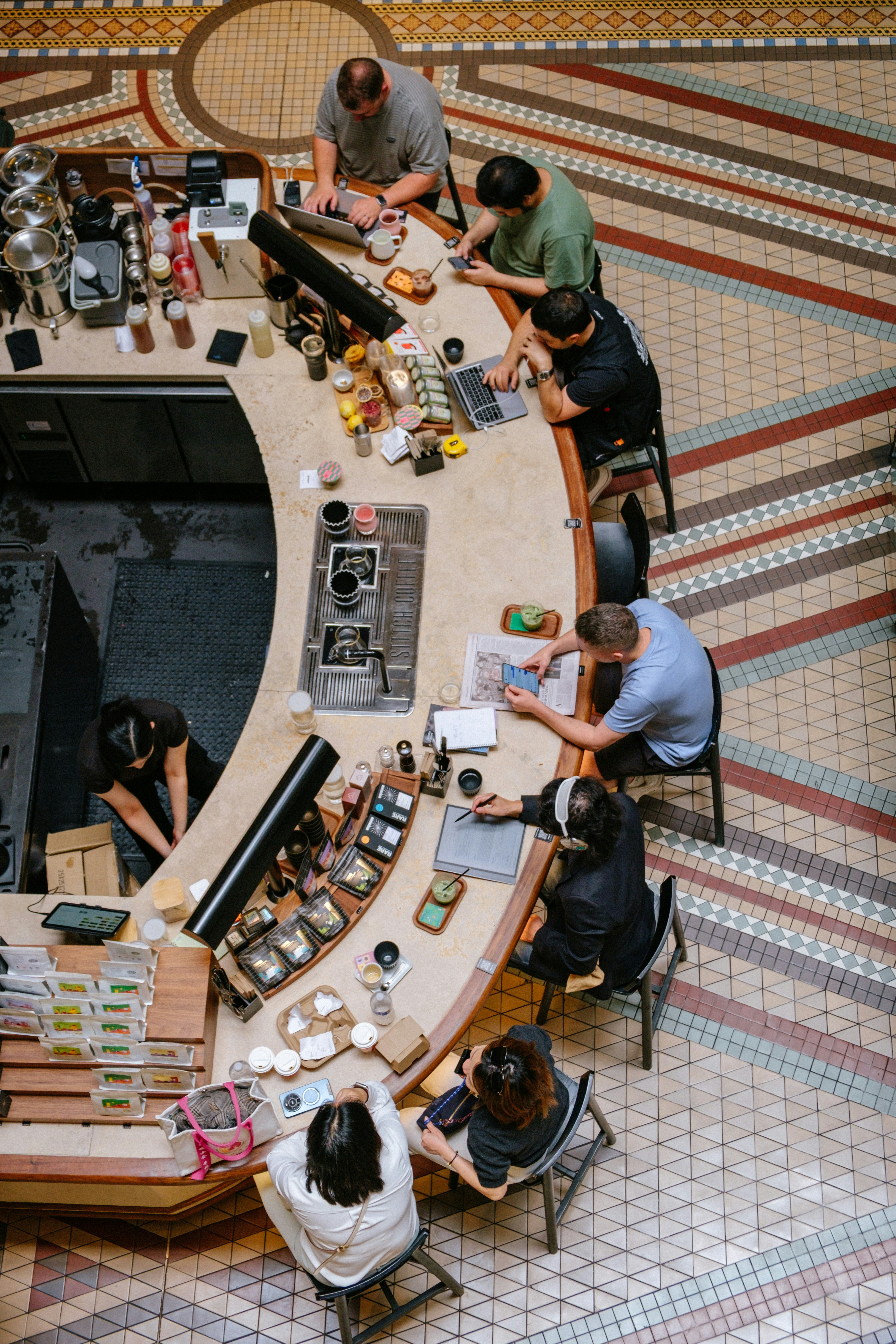 People working and socializing at a modern cafe counter.
