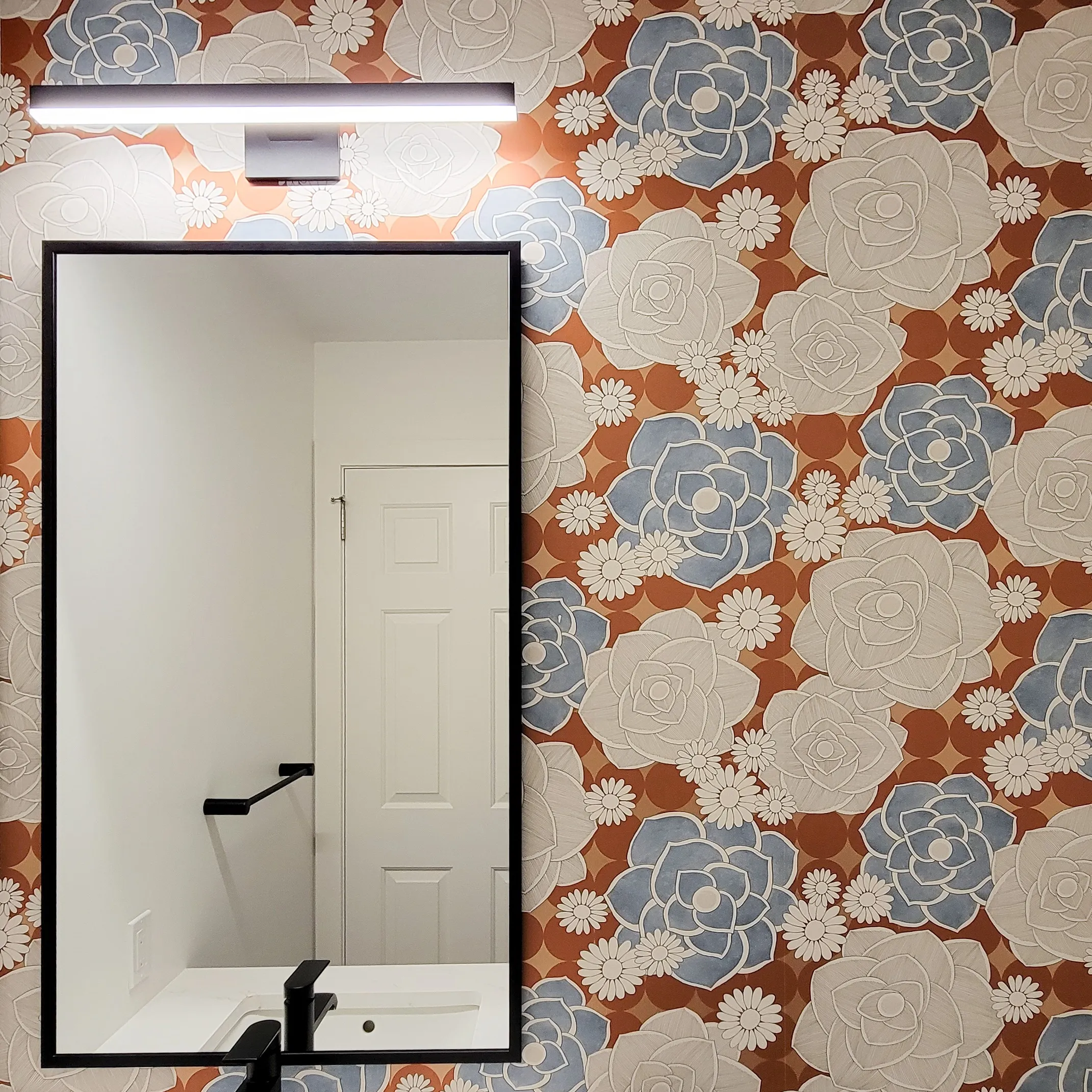 Image of powder room vanity mirror with blue and white flower wallpaper.