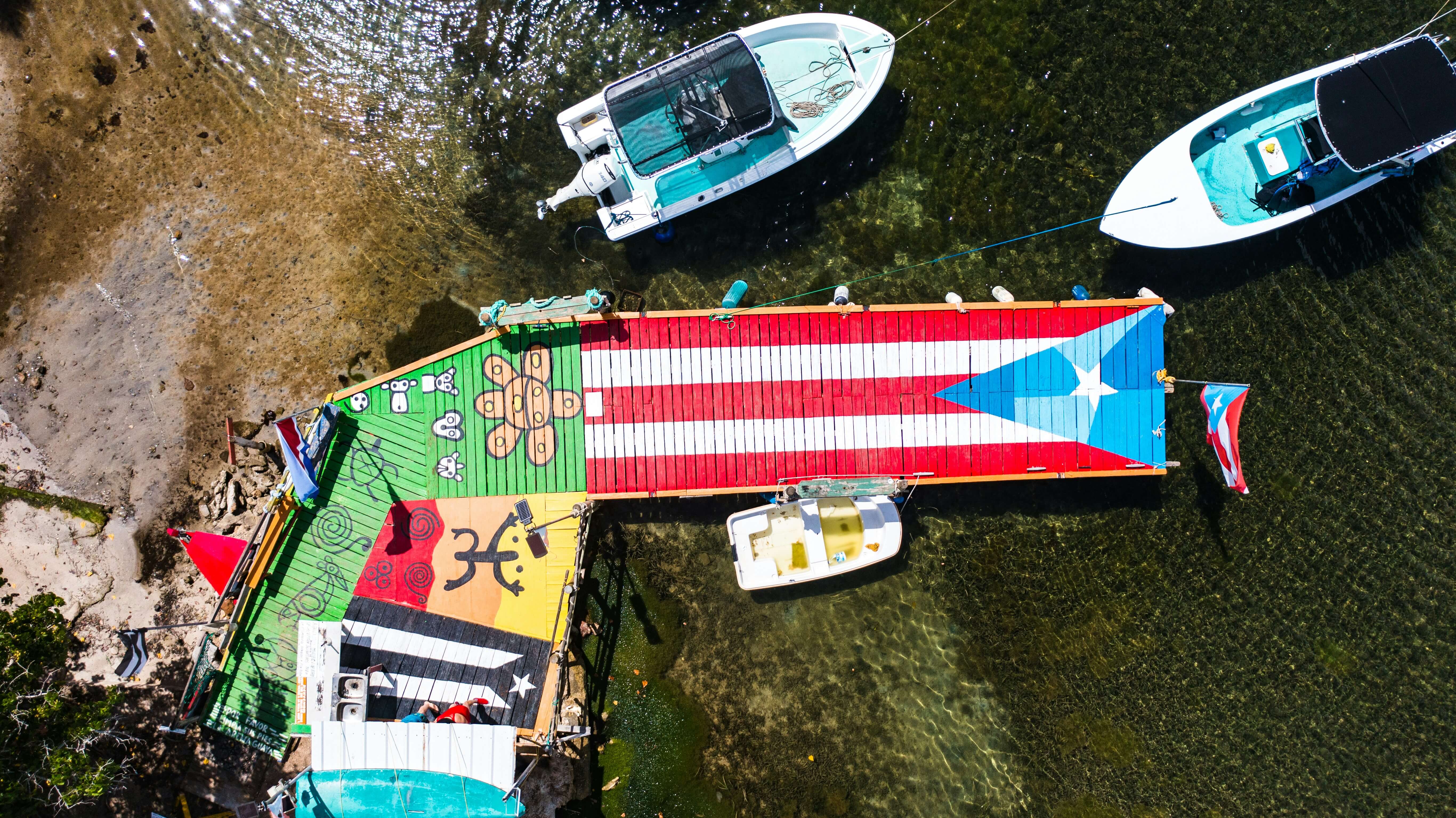 Colorful dock painted with the Puerto Rican flag, surrounded by boats on clear shallow waters in Vieques, Puerto Rico.