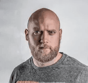 Man with beard wearing grey graphic t-shirt, looking directly at camera against white background