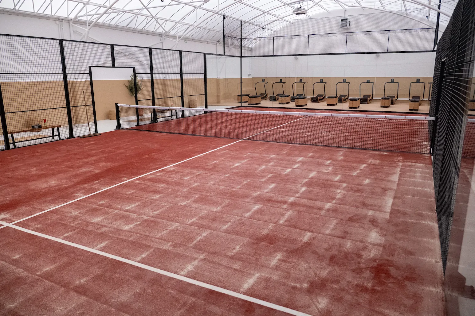 Terrain de padel intérieur, vue générale avec filet et lignes blanches.