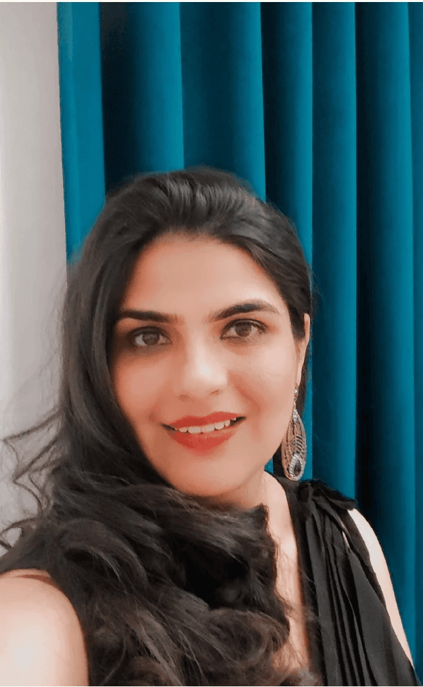 Portrait of a young man with wavy dark hair and a trimmed beard in a white sweater, soft light on a neutral background.