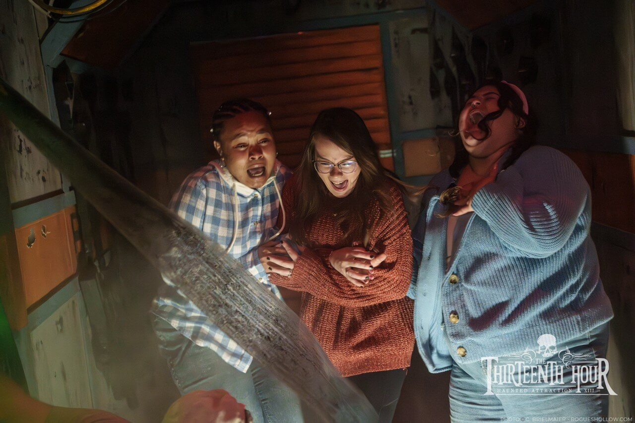 Three guests scream as a scare actor lunges toward them