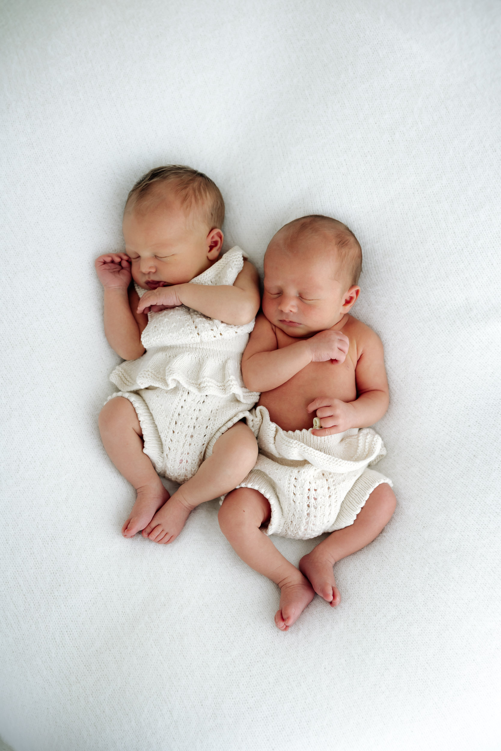 Twin newborn photography session in Mackay studio, two sleeping babies wrapped in soft neutral tones.