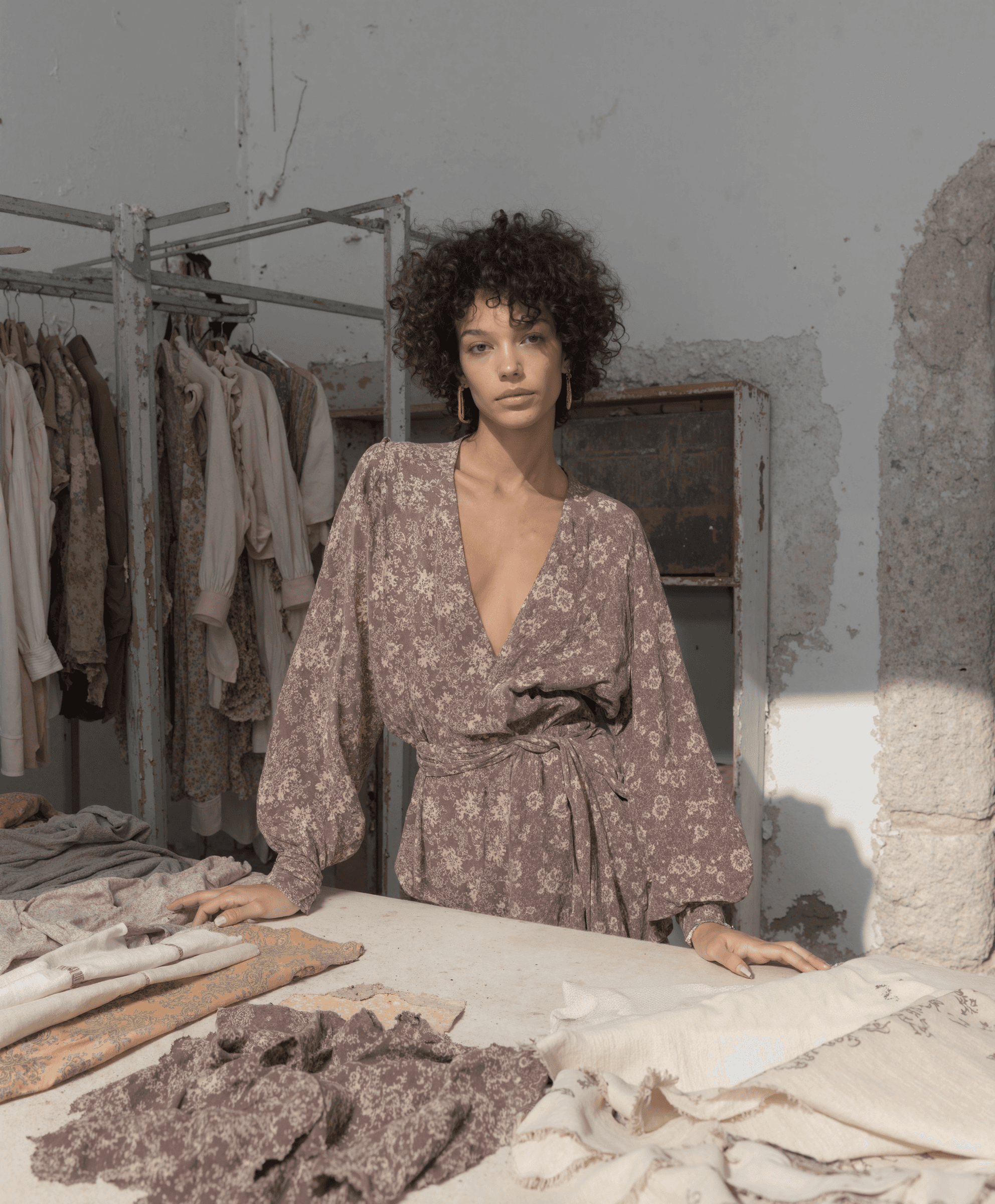 AI-generated editorial image of a woman in a brown patterned wrap dress inside an artisan studio, created by Myrovia Labs for La Fabrique. AI fashion photography highlighting texture, craft, and quiet luxury.