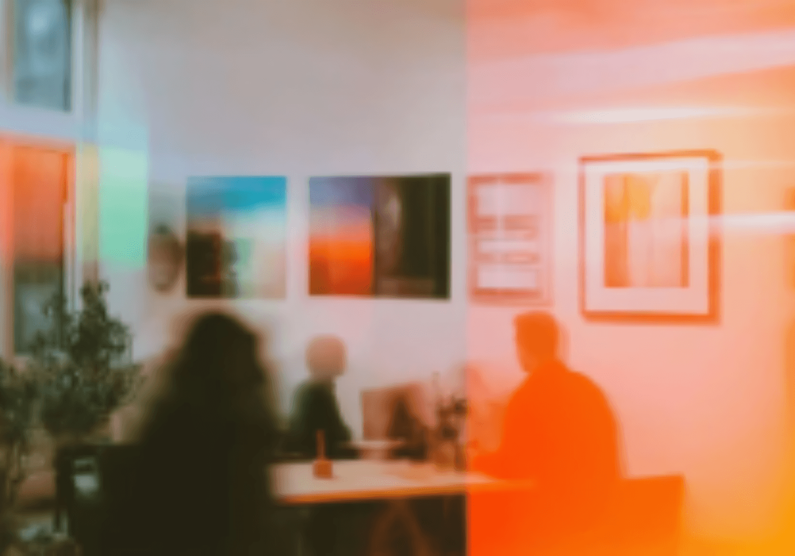 A smiling man and woman in black shirts sitting together outdoors, engaged in conversation, with a white building in the background.