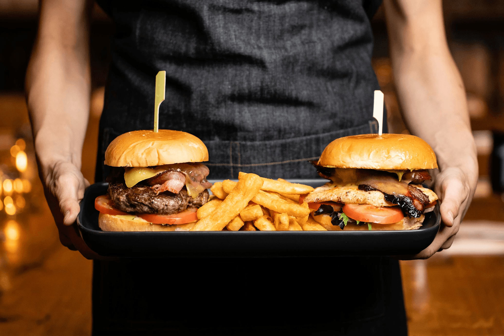 waiter holding 2 burgers on a tray