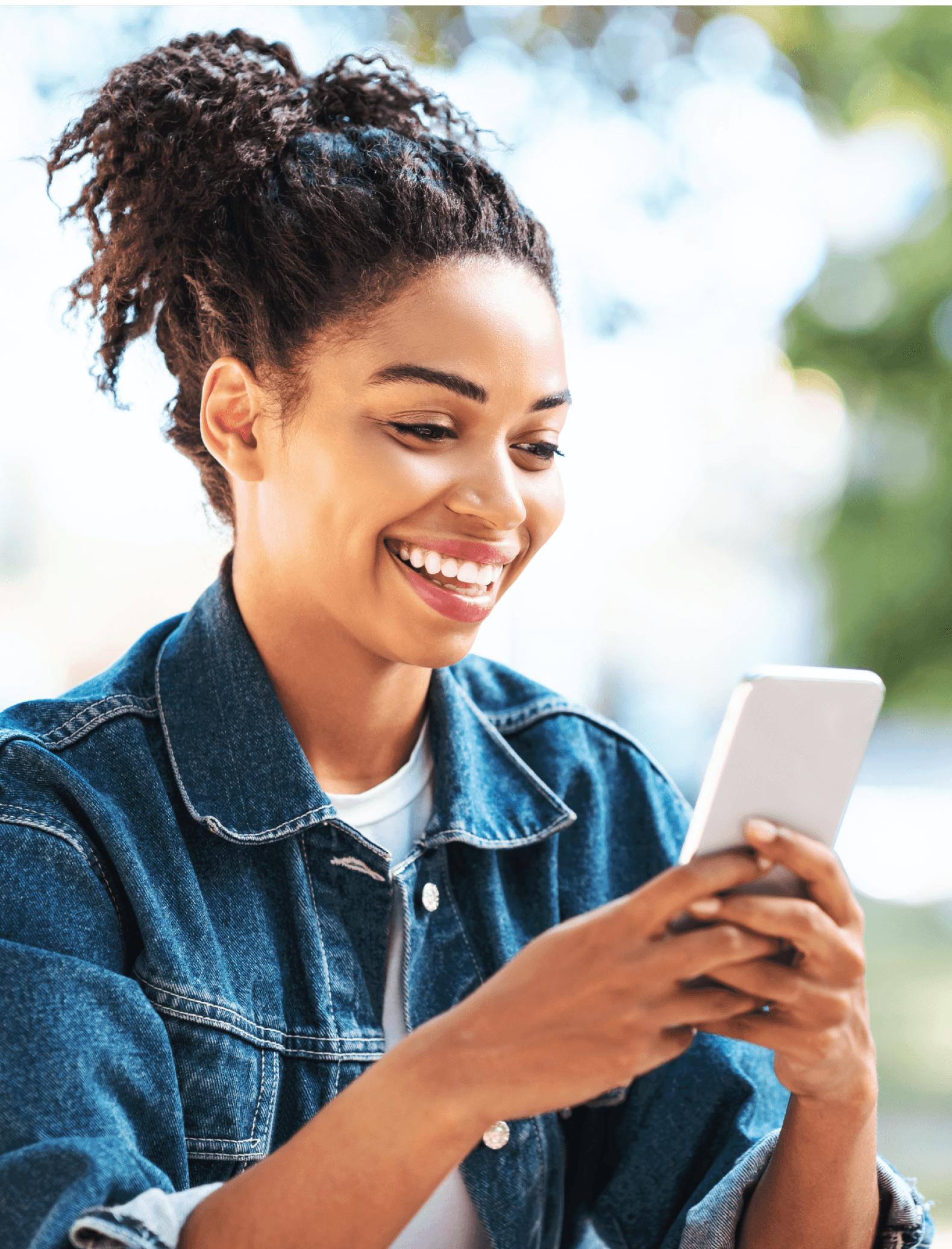 Black woman with a smile on the outside using a cellphone