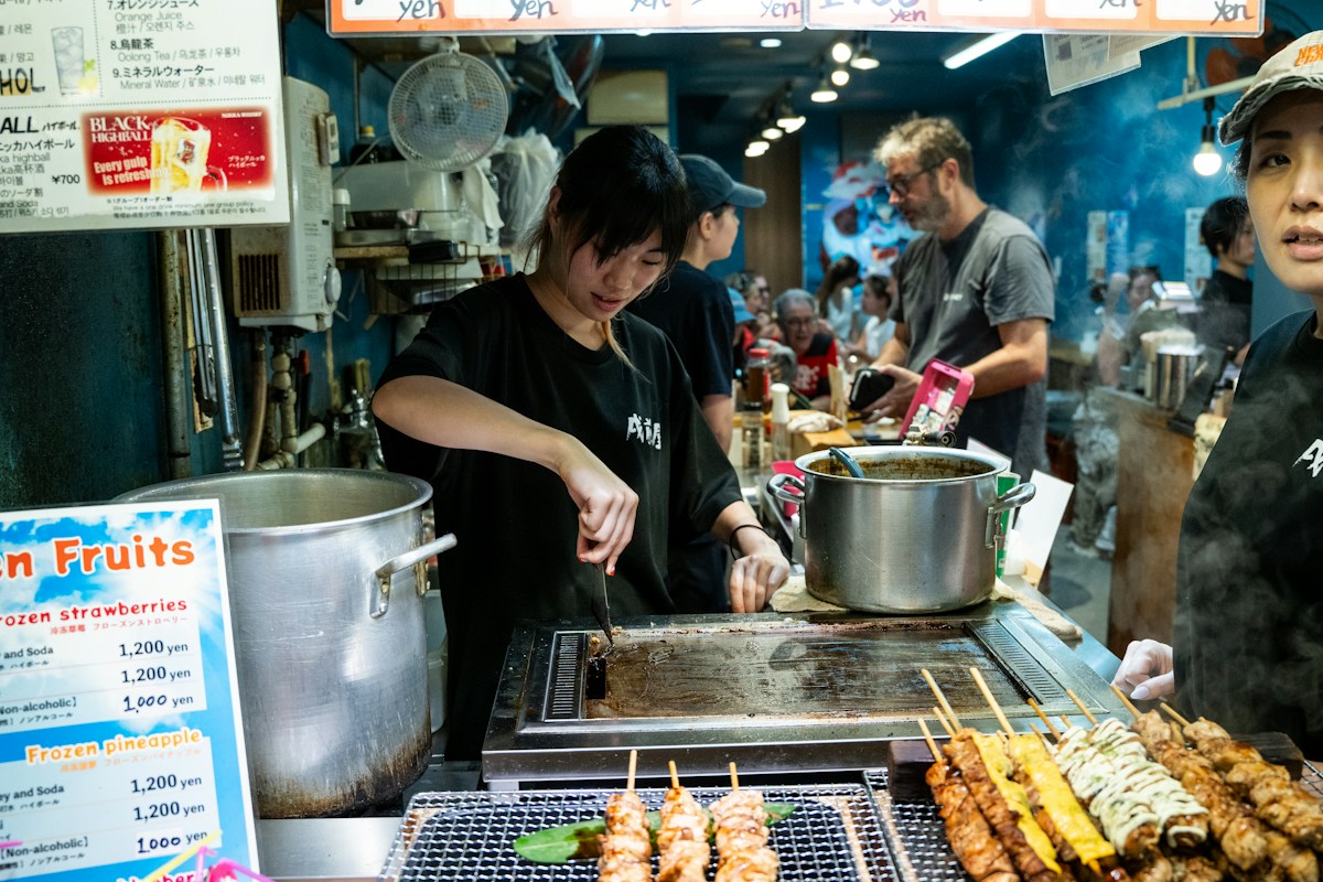 Vendor grilling skewers at a Japanese food market stall