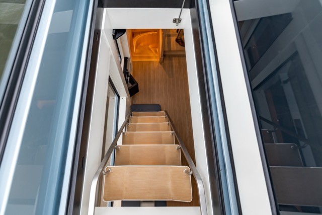 Top-down view through an open companionway hatch showing EcoDeck composite material used for interior stair treads, demonstrating the product's versatility for below-deck and companionway applications with a warm light oak finish and non-slip surface