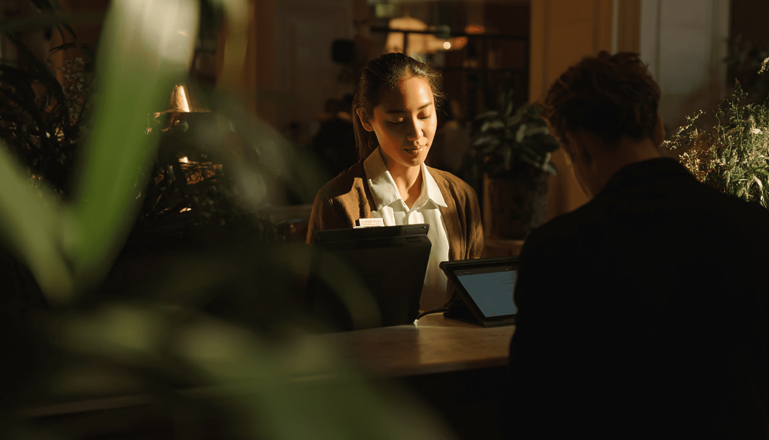 Modern office building with large windows reflecting a vivid orange sunset sky, silhouetted figure visible through the glass.