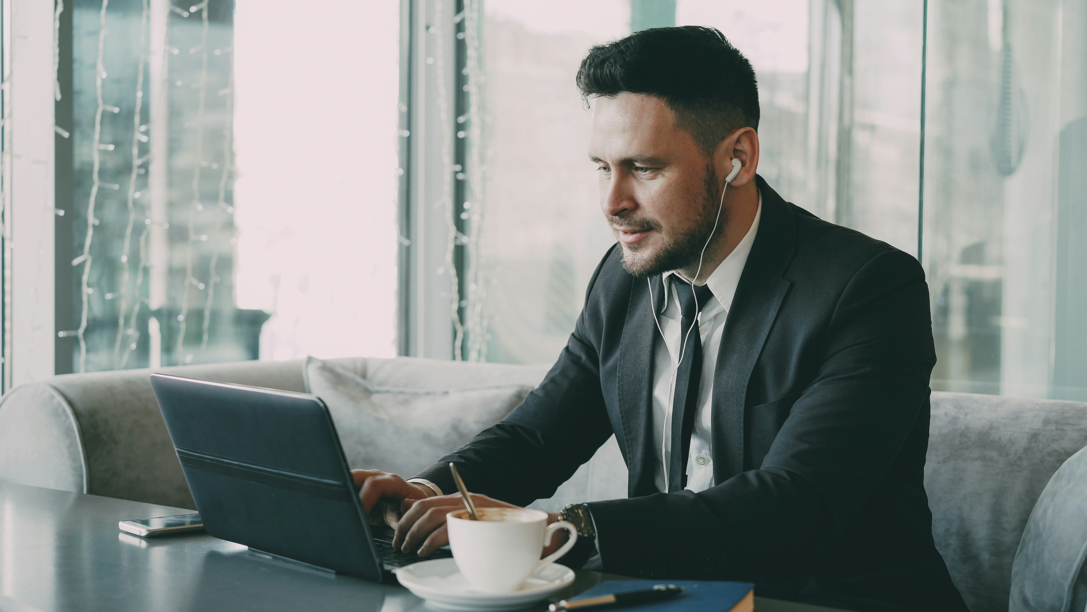 Man in suit working on laptop with coffee.