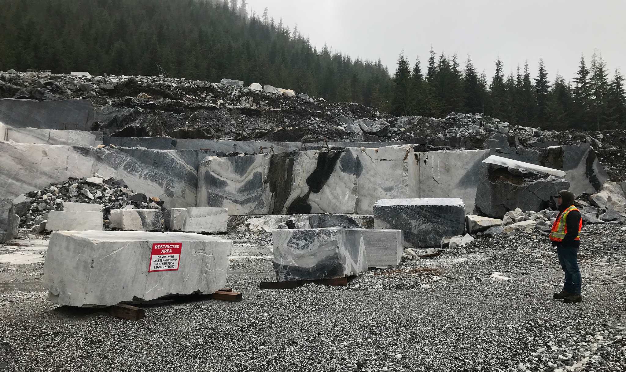 Engineer inspecting marble blocks at Callache Quarry pit with restricted area signage