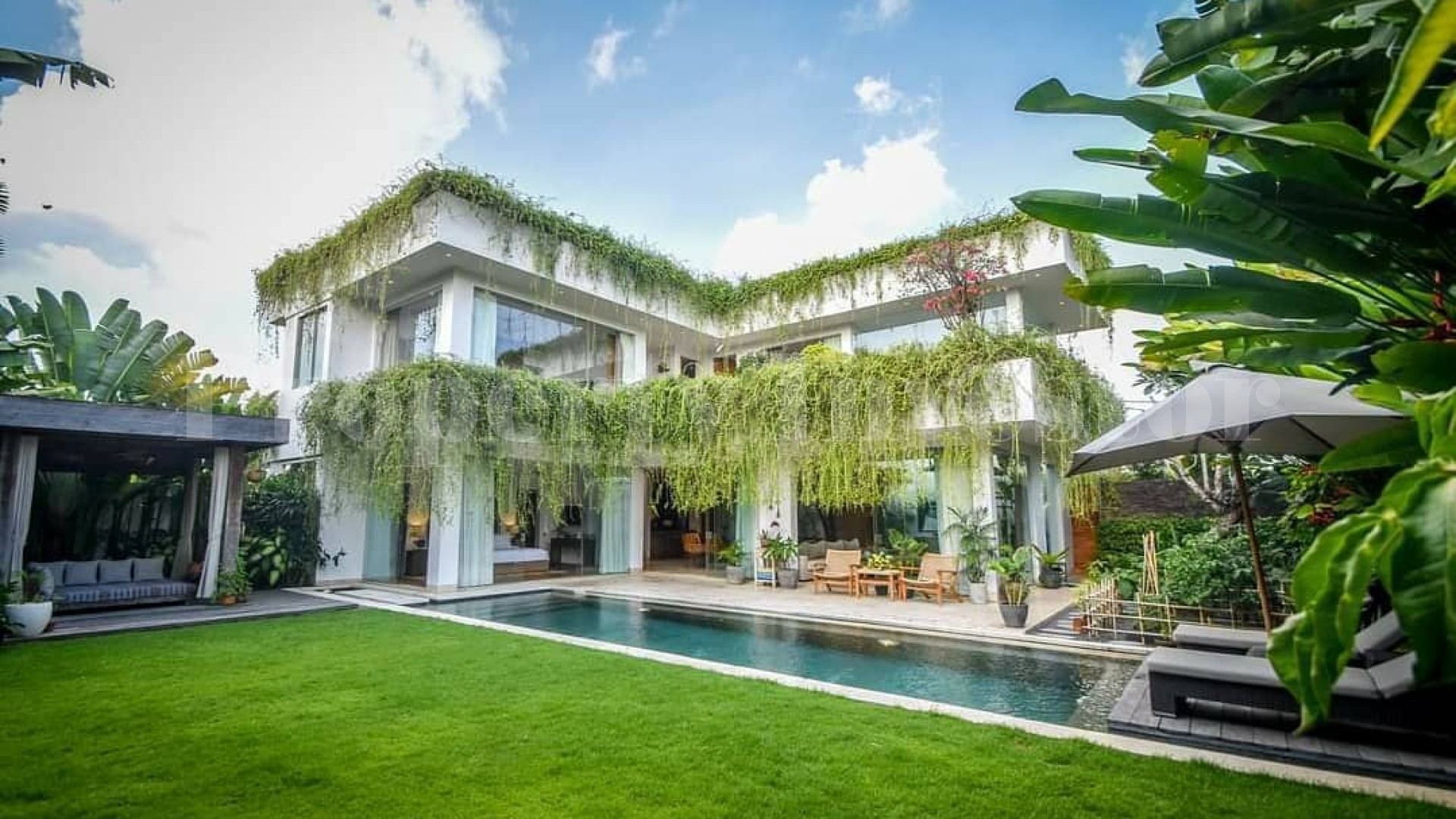 Exquisite two-story tropical villa with lush green hanging plants and a large garden in Canggu.