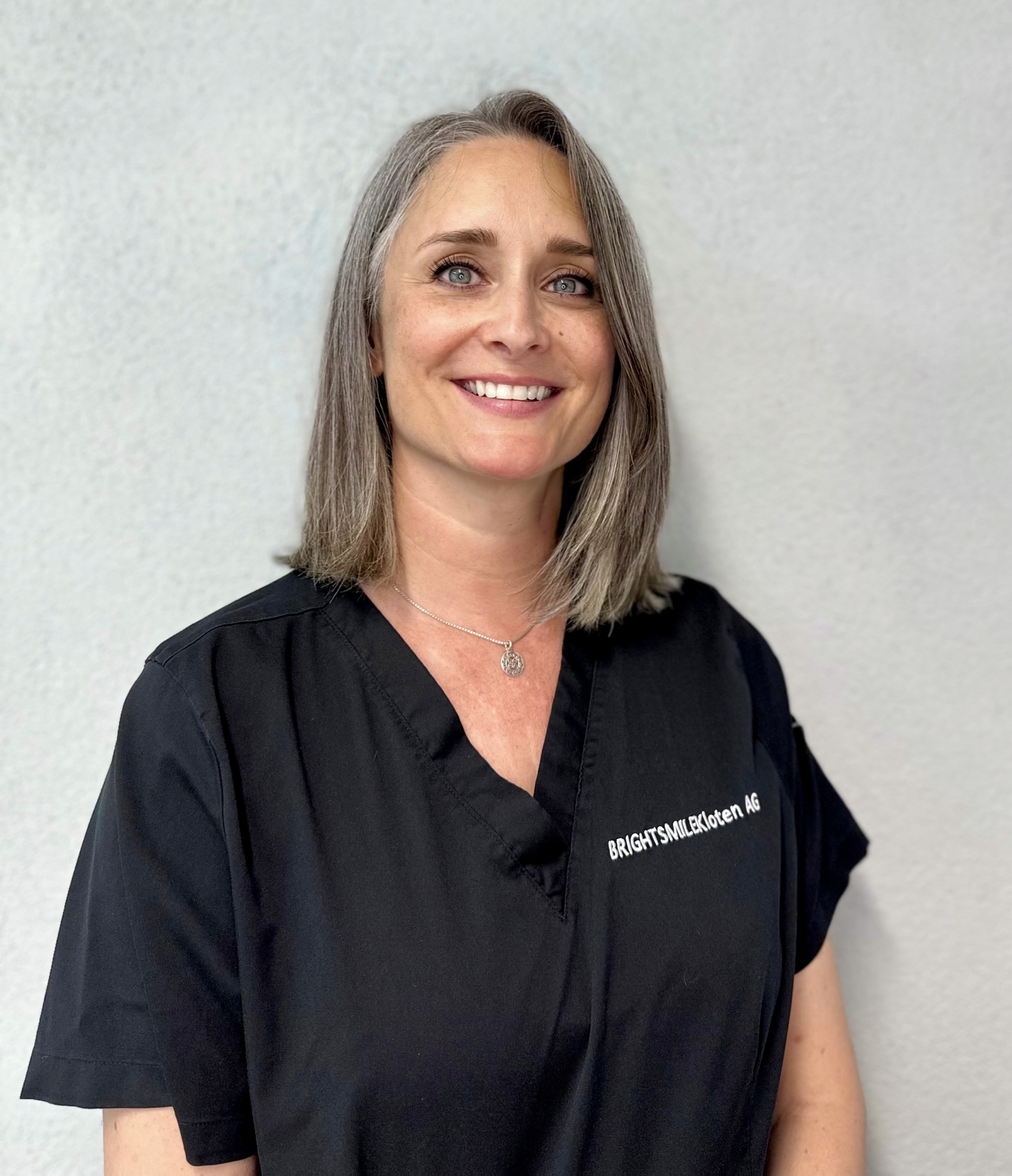 Prophylaxeassistentin Gabriela Brunner im Portrait mit kurzem Haar und breitem Lächeln. 