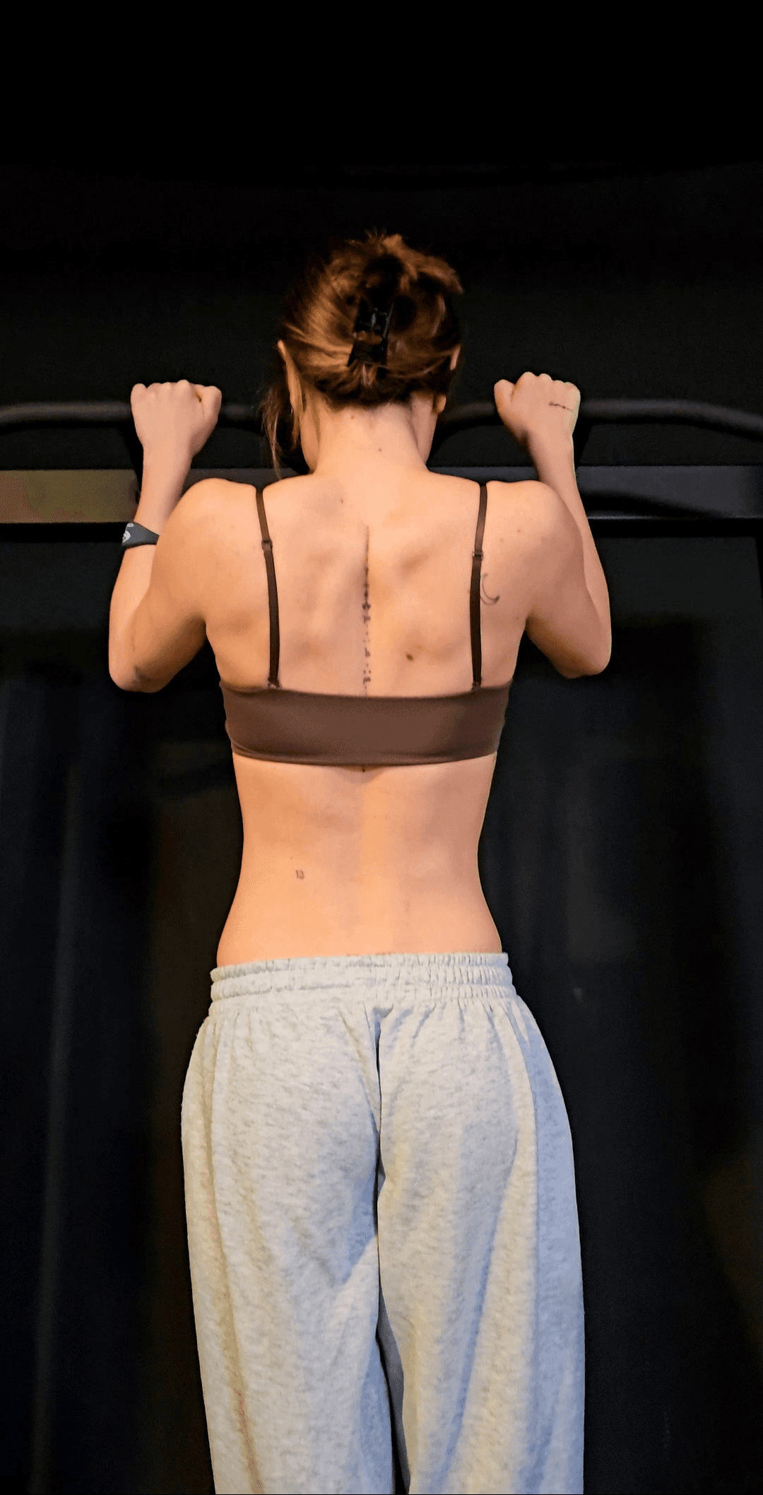 Chica realizando dominada durante entrenamiento personal en Alicante