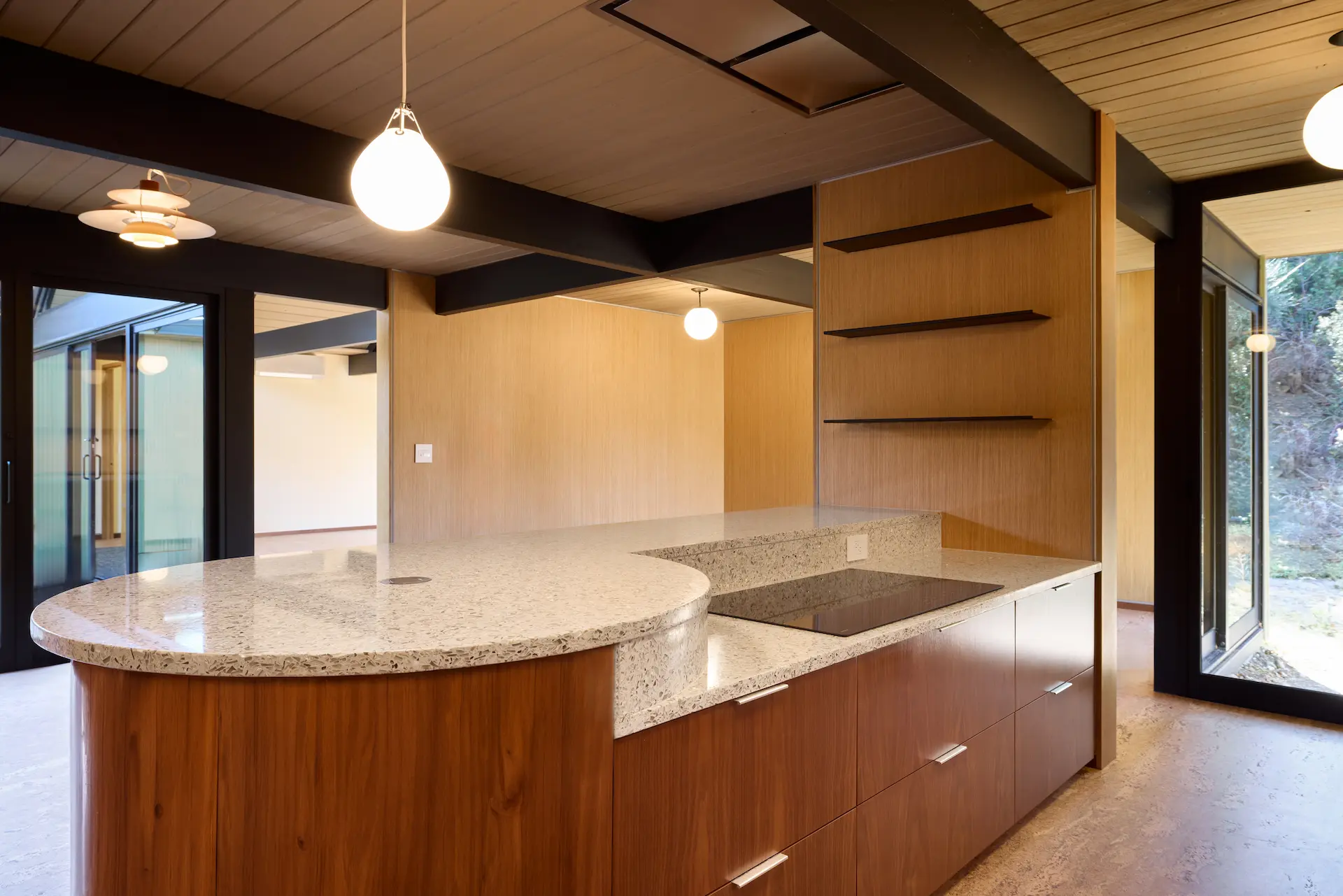 Angled view of the kitchen island, featuring a quartz waterfall edge and modern seating area in the Fairhills Eichler Tract remodel. Photo by Todd Huge.