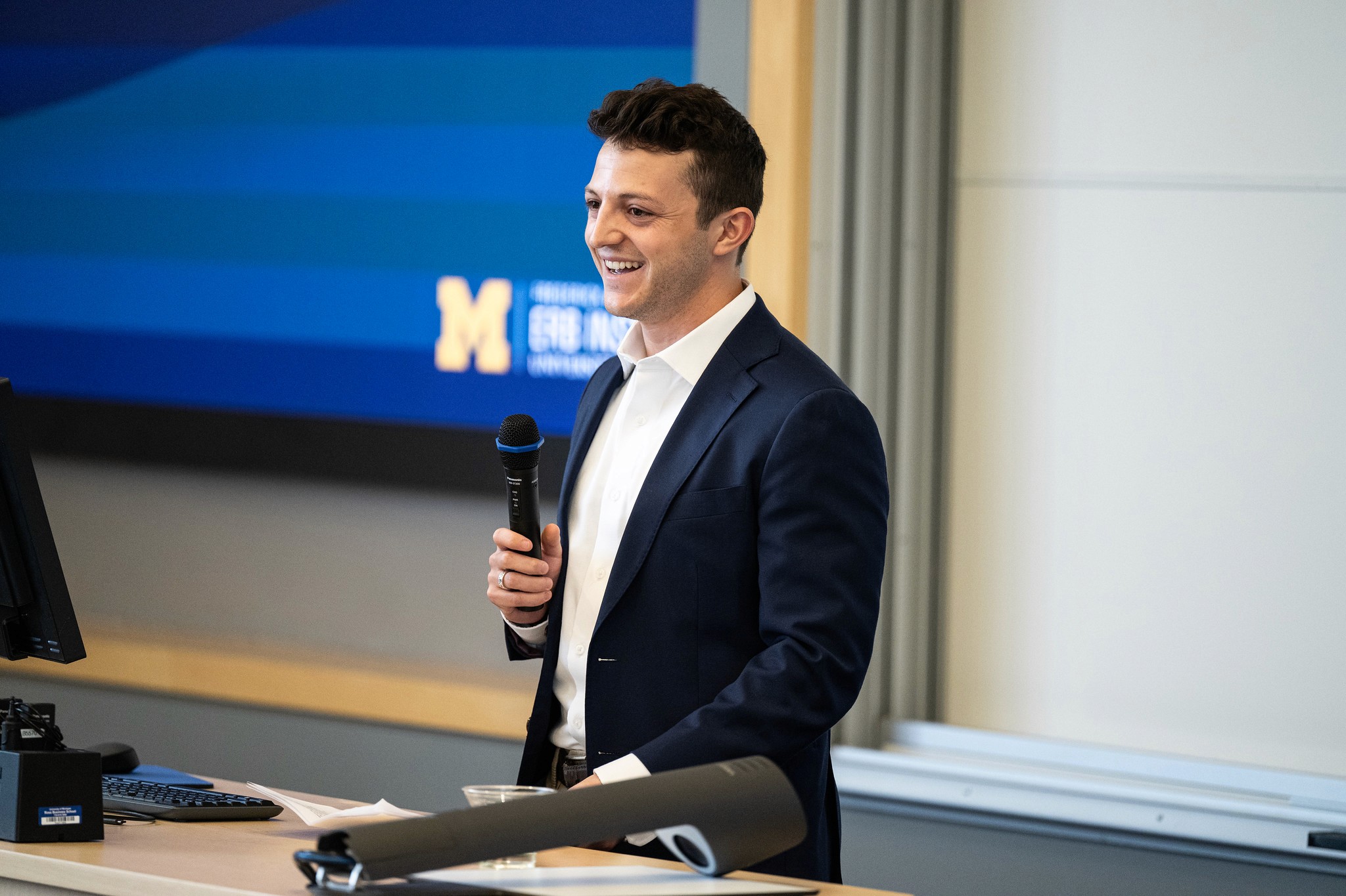 Erb alum Zachary Marmet holds a microphone and smiles