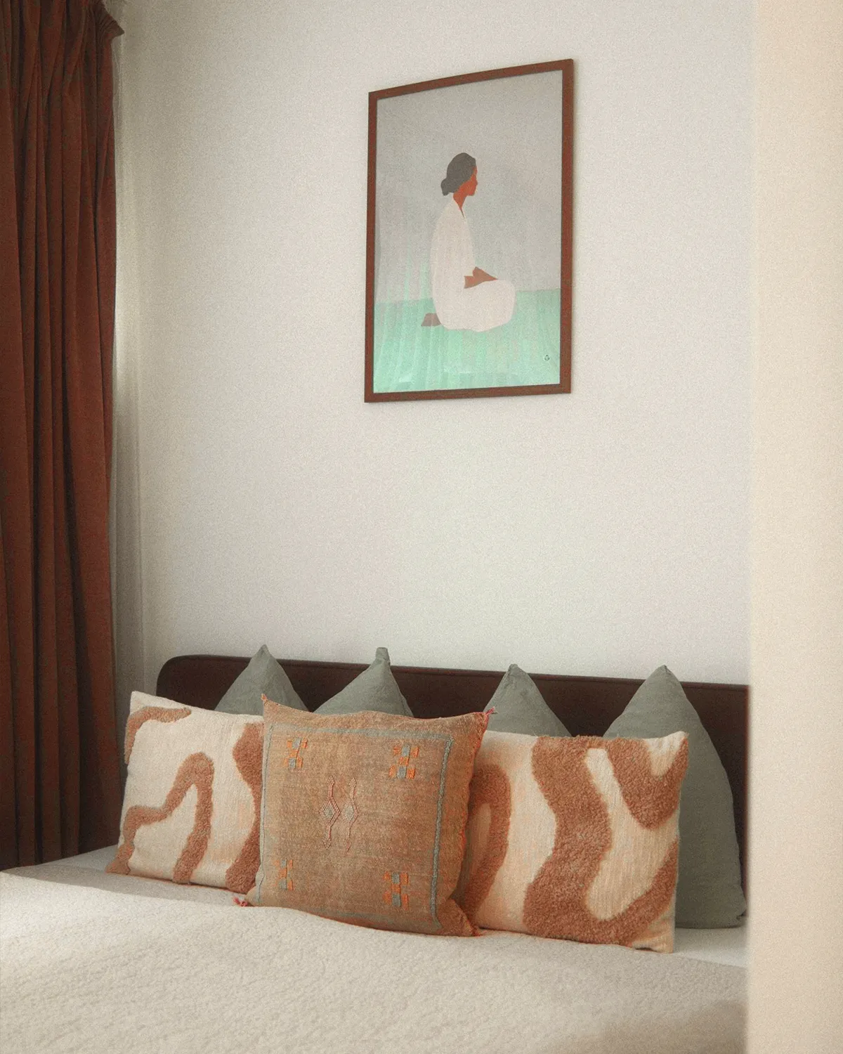 Urban N°1 • bed with patterned cushions below a framed illustration