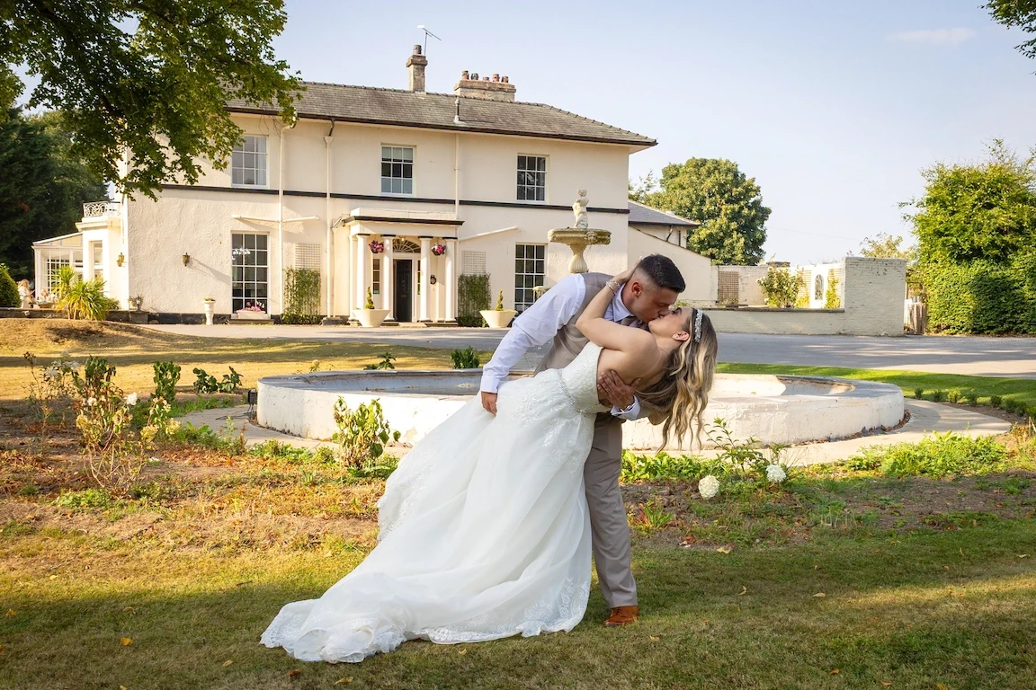 Bride and groom sharing a kiss in the gardens of a wedding venue near Chester