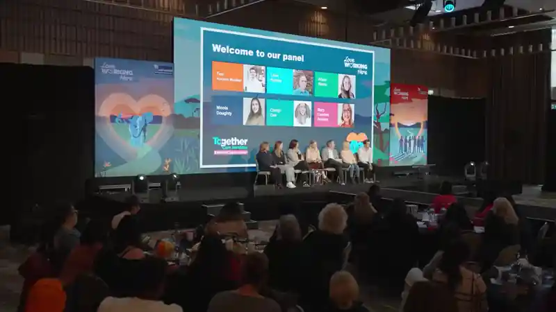 Panel discussion on stage at a Bupa Care leadership event, with live content displayed on the main screen.