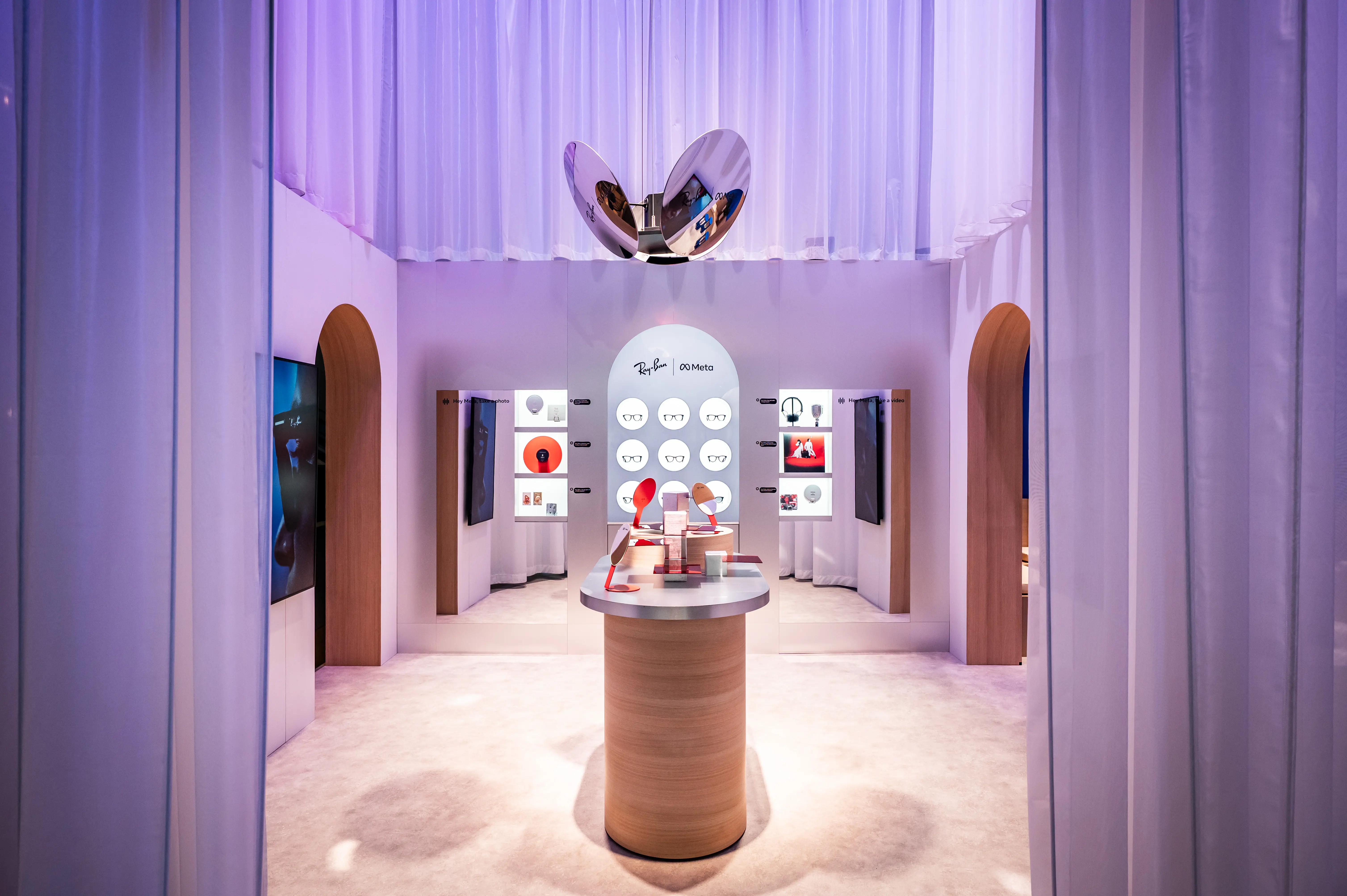 Ray-Ban Meta zone in soft white with arched wooden doorways, product walls and central display counter.