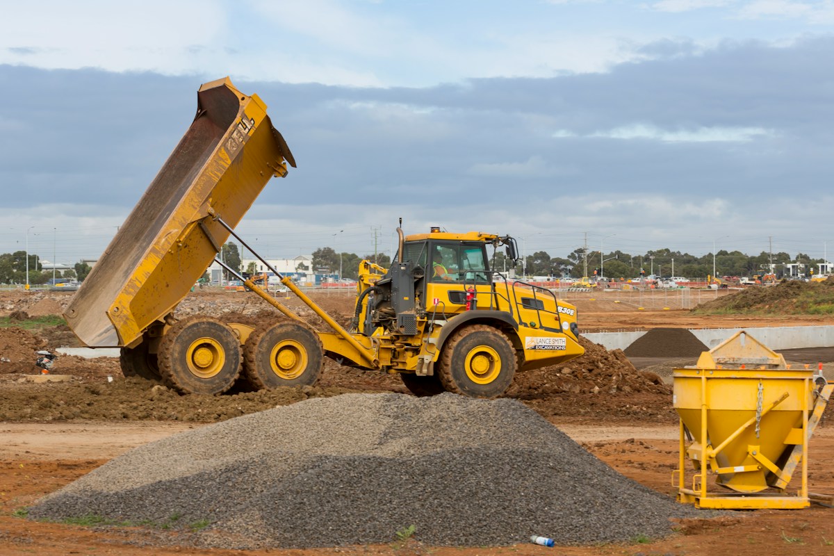 Wheel loader dumping aggregate material into a dump truck on a job site