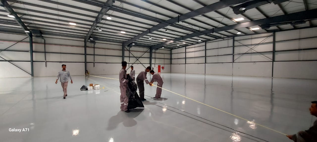 High-gloss epoxy flooring installation in a large hangar