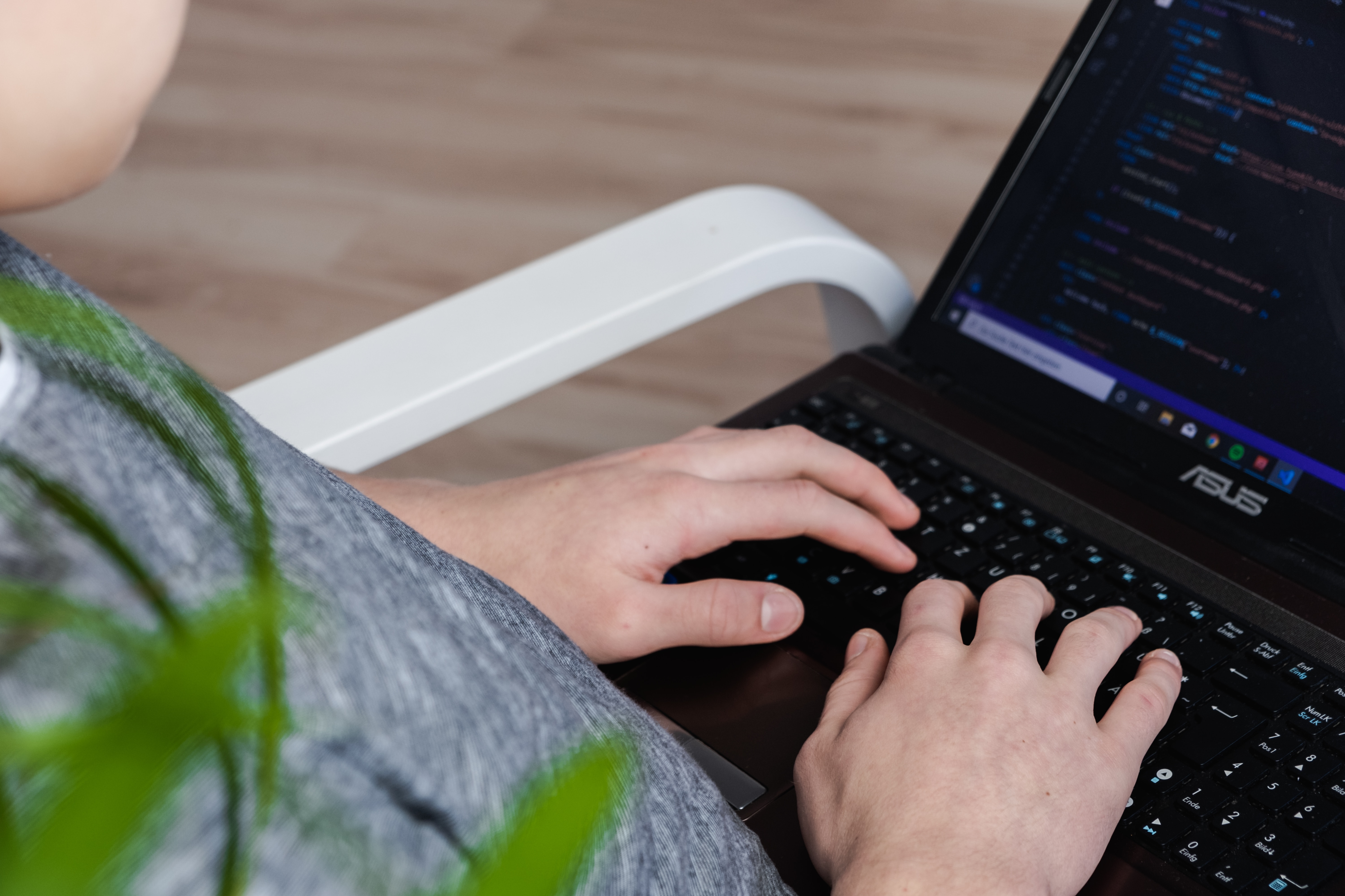 A person working on a laptop with a coding program on it.