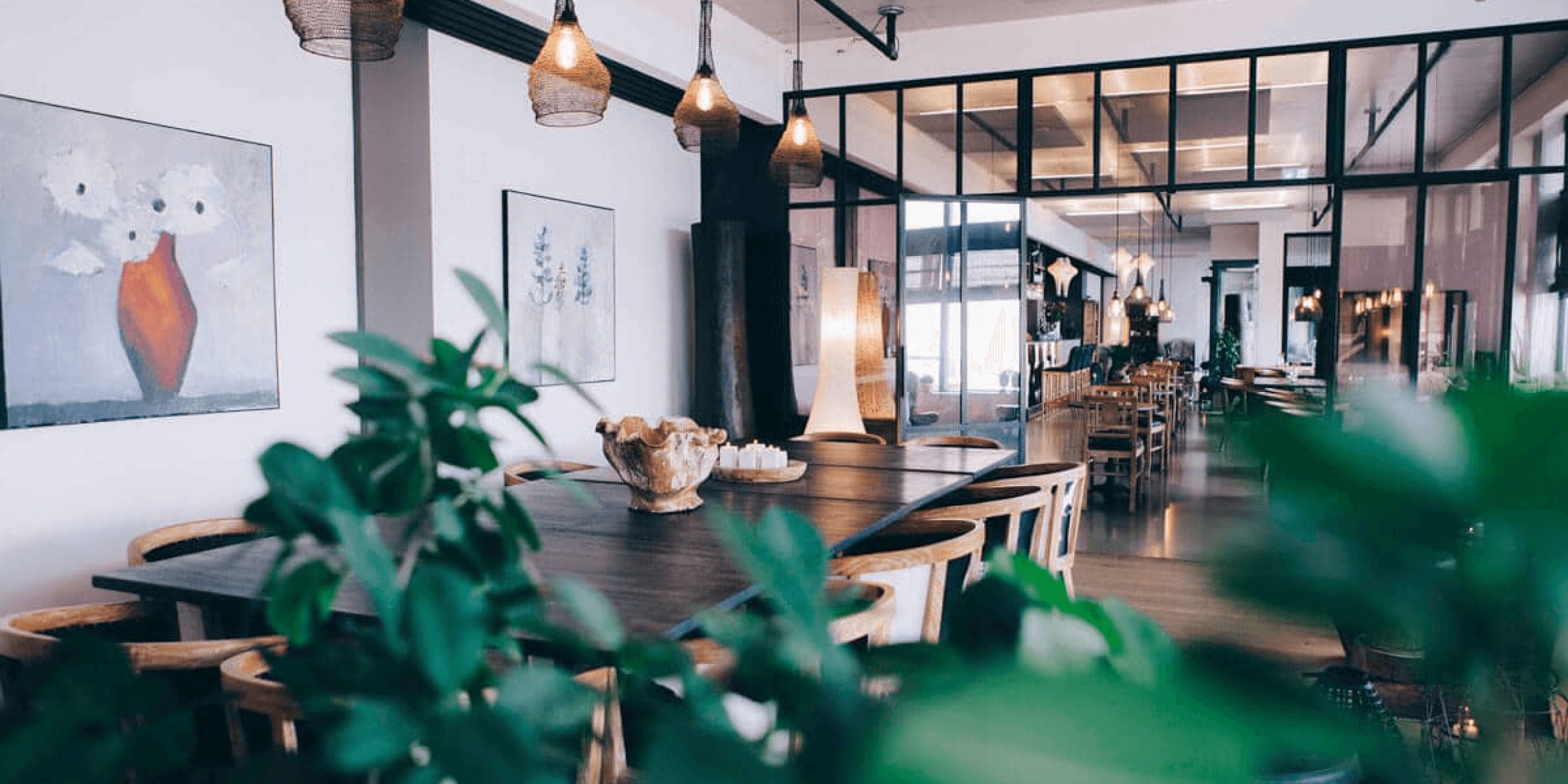 Modern hotel restaurant interior with wooden tables, hanging pendant lights, and a bright open layout